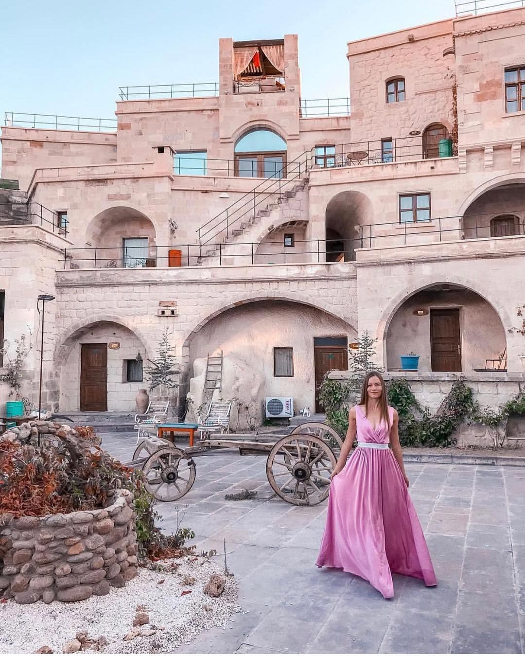 Doors of Cappadocia'nın taş avlusunda, arkada mağara otel odalarının kemerli cepheleri