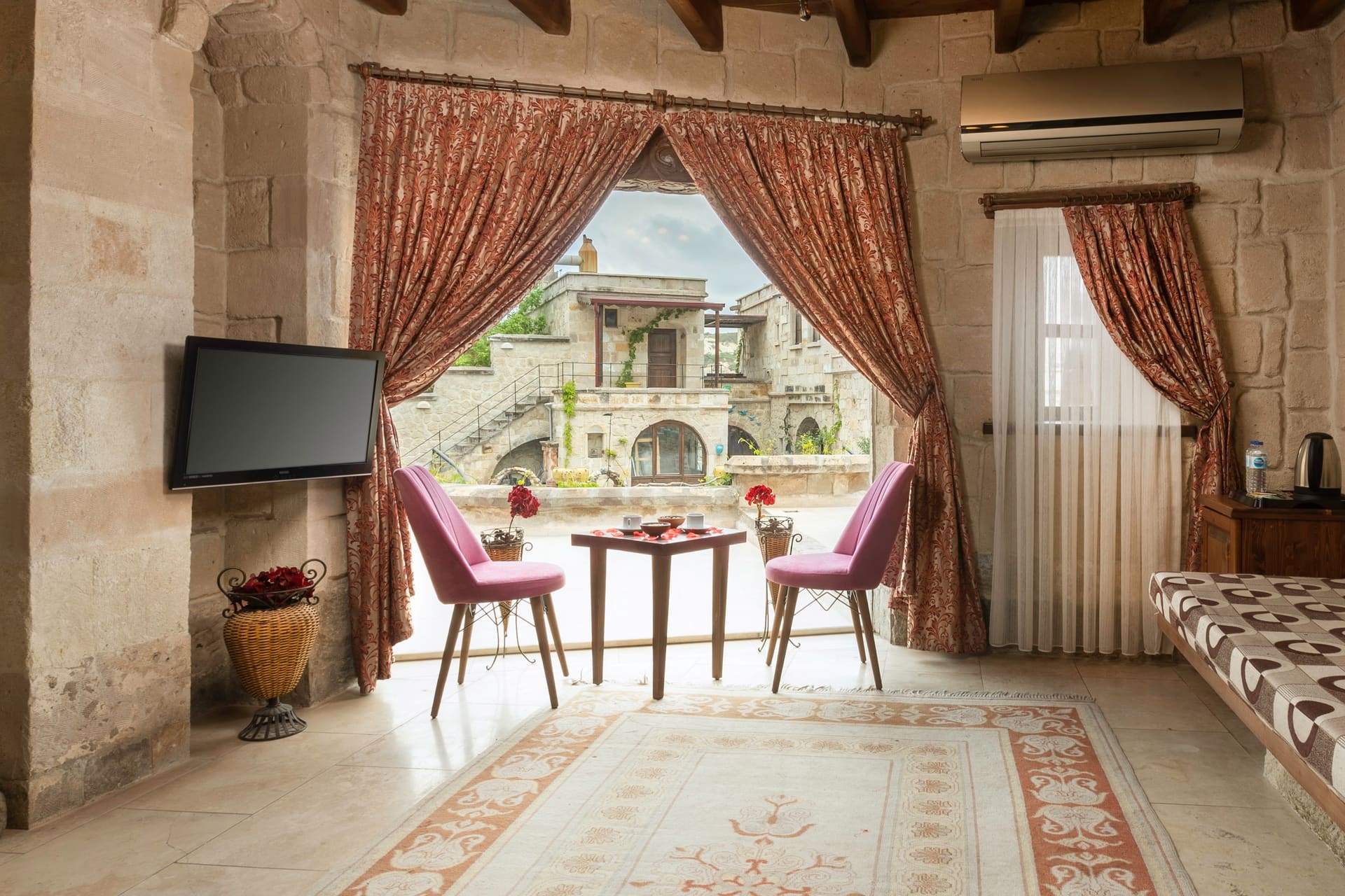 Room 111, King Cave Suite: the same terrace corner from another angle, with an air conditioner, a small bar shelf, and a patterned bench