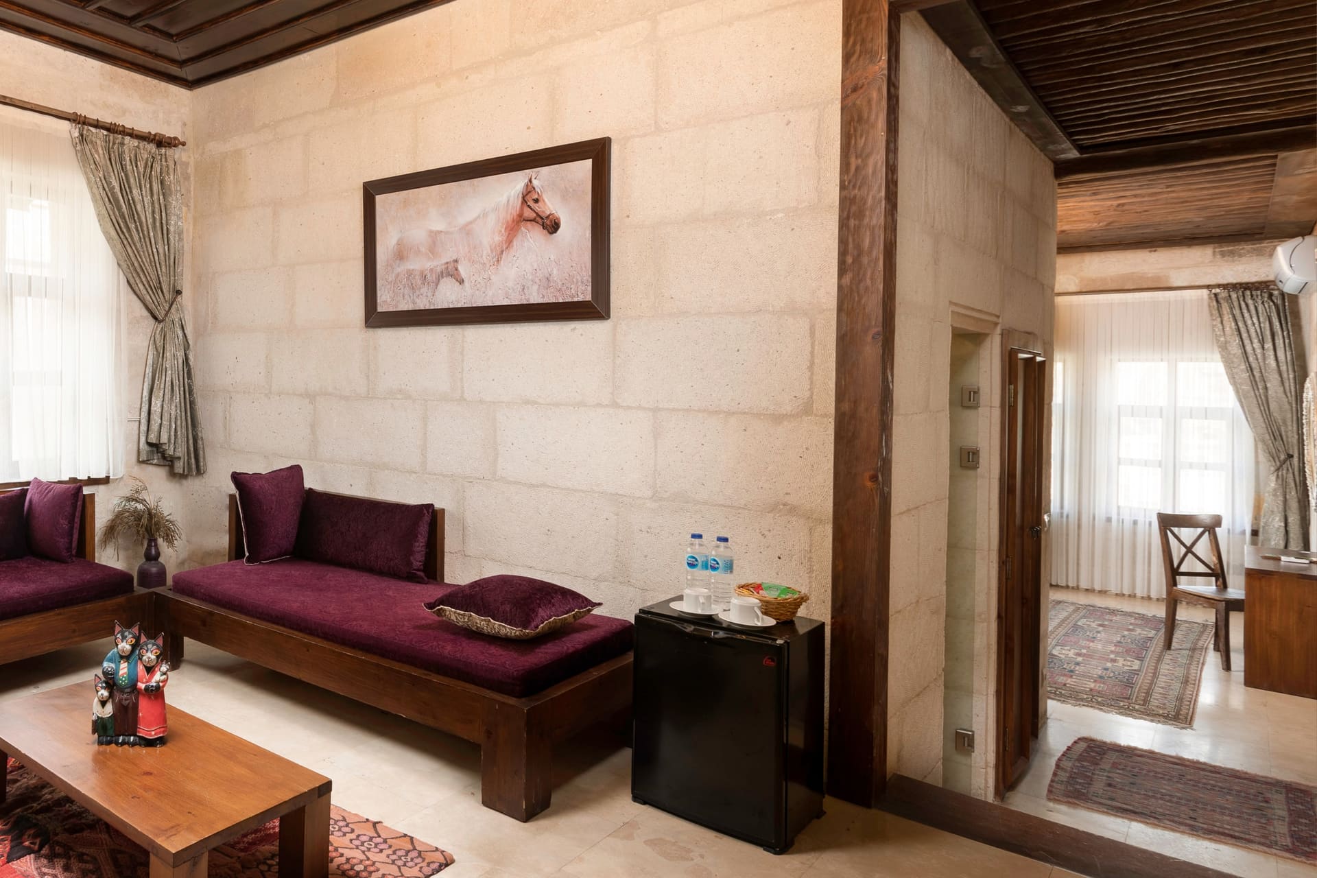 Room 117, Junior Suite: Purple sofas, coffee table, doorway to hall, curtained window.