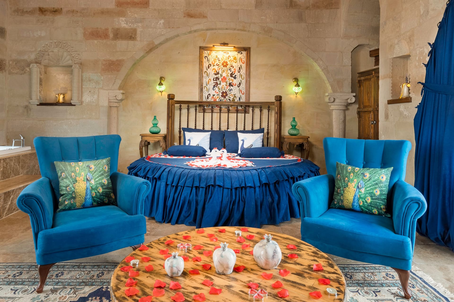 Room 120, Queen Suite: Round bed with a blue skirted base, a painting in the stone niche, wooden door.