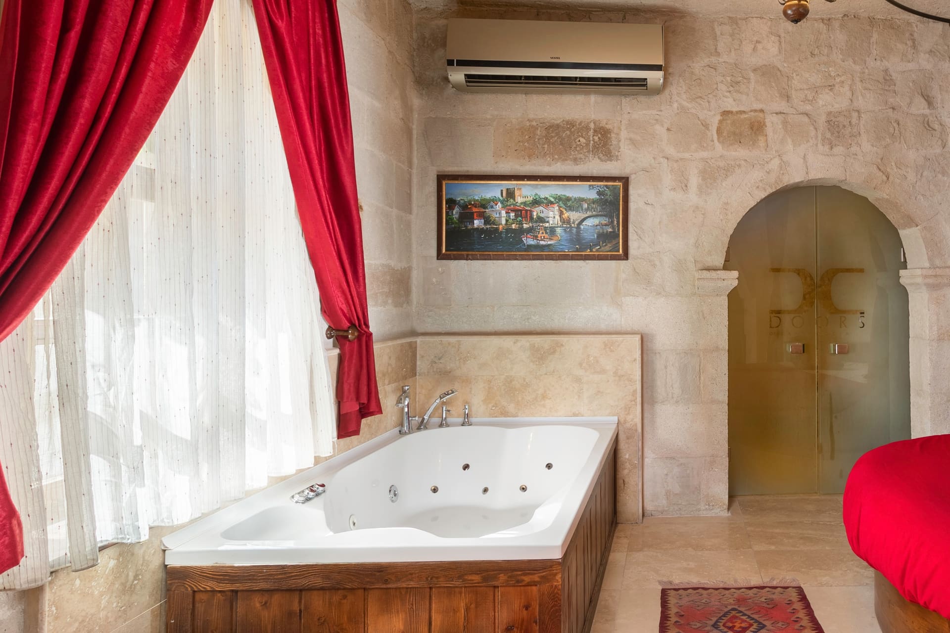 Room 107, King Suite: close view of the round red bed with the arched doors behind it