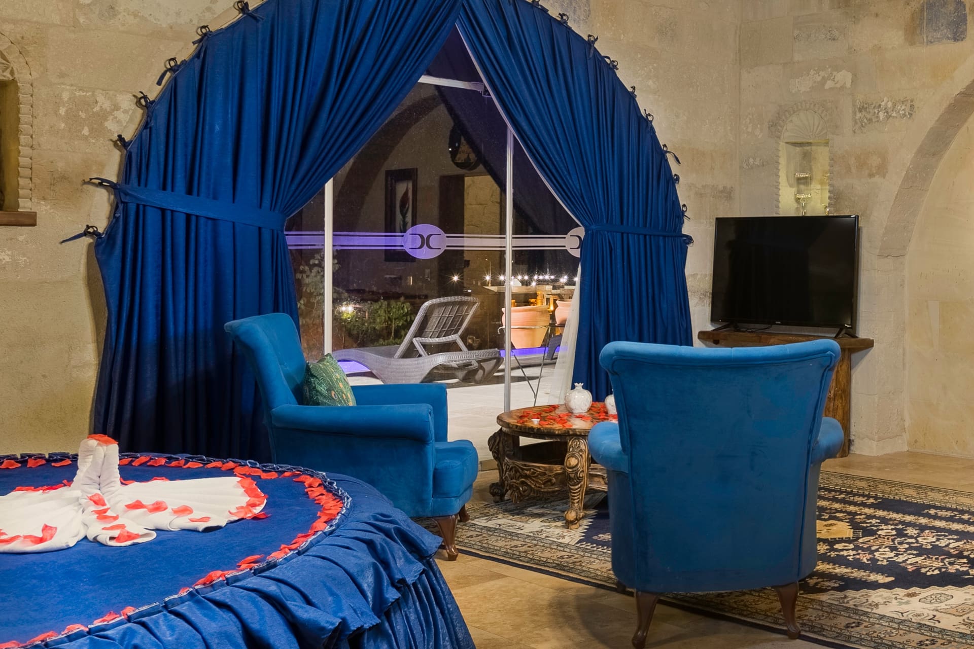 Room 120, Queen Suite: The bed area from another angle, blue armchair and terrace door.