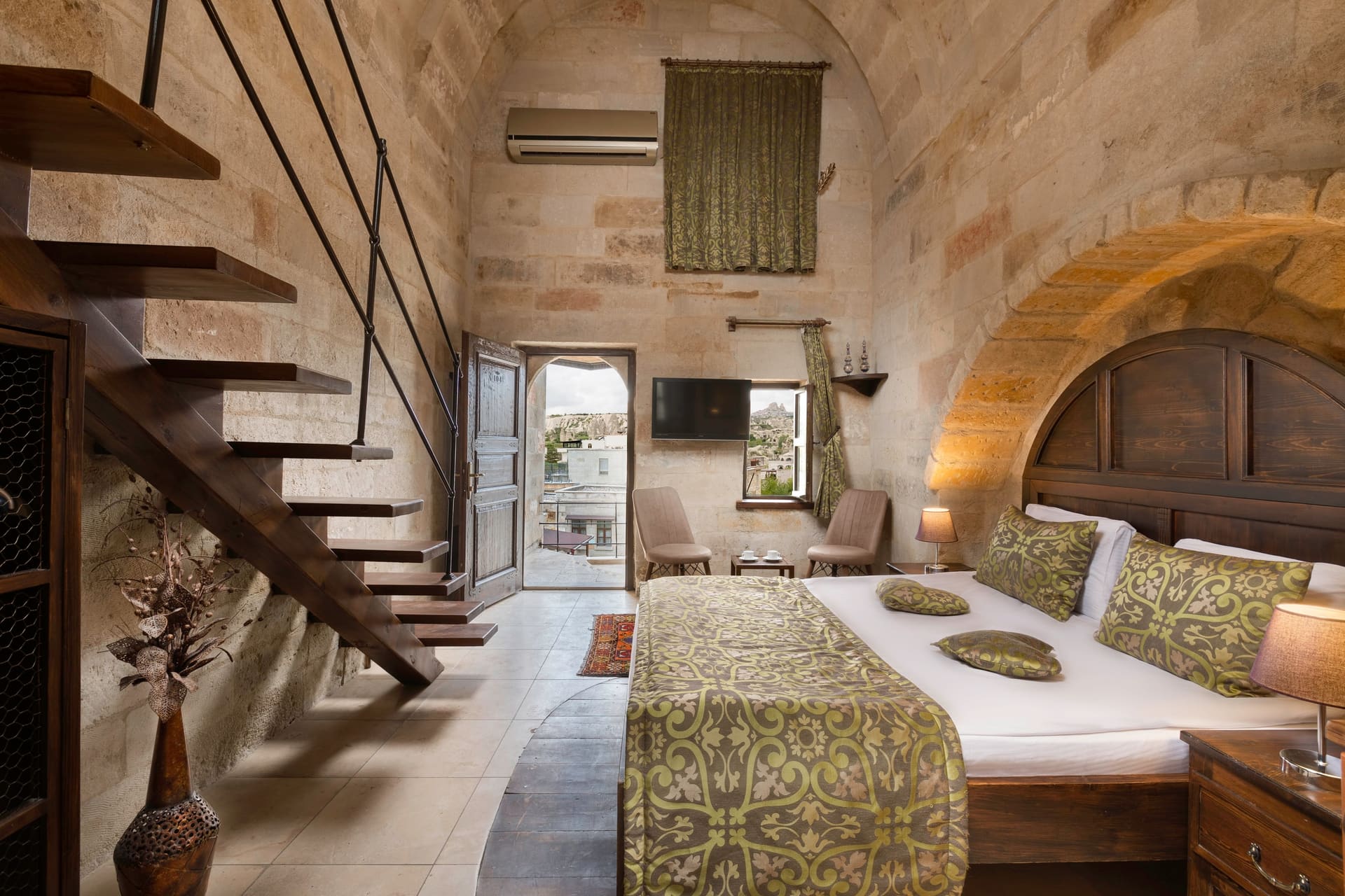 Room 104, Junior Suite: Staircase to mezzanine loft, arched bed alcove, wall-mounted TV.