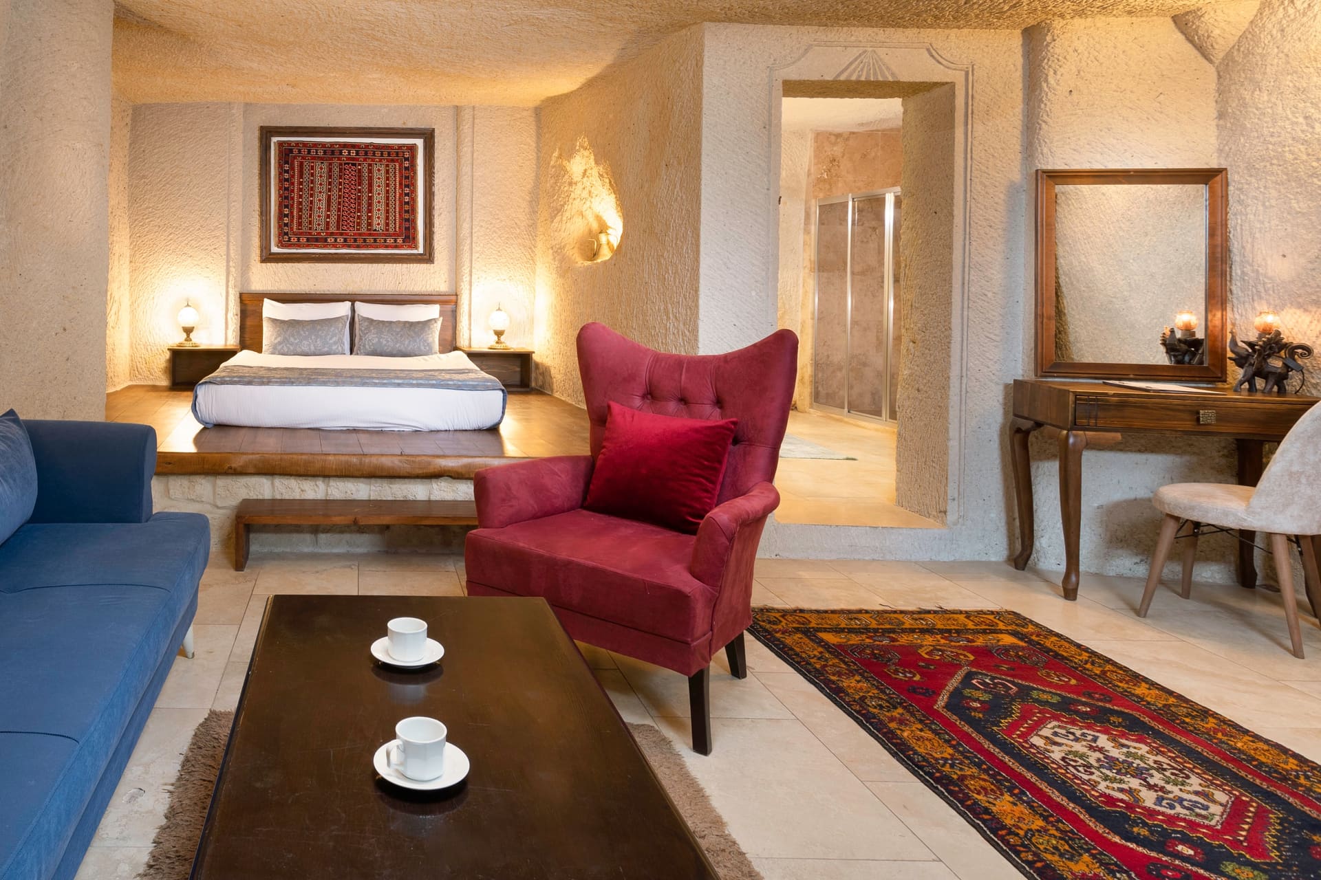 Room 114, Junior Cave Suite: bed in the foreground, blue sofa and mirrored console behind