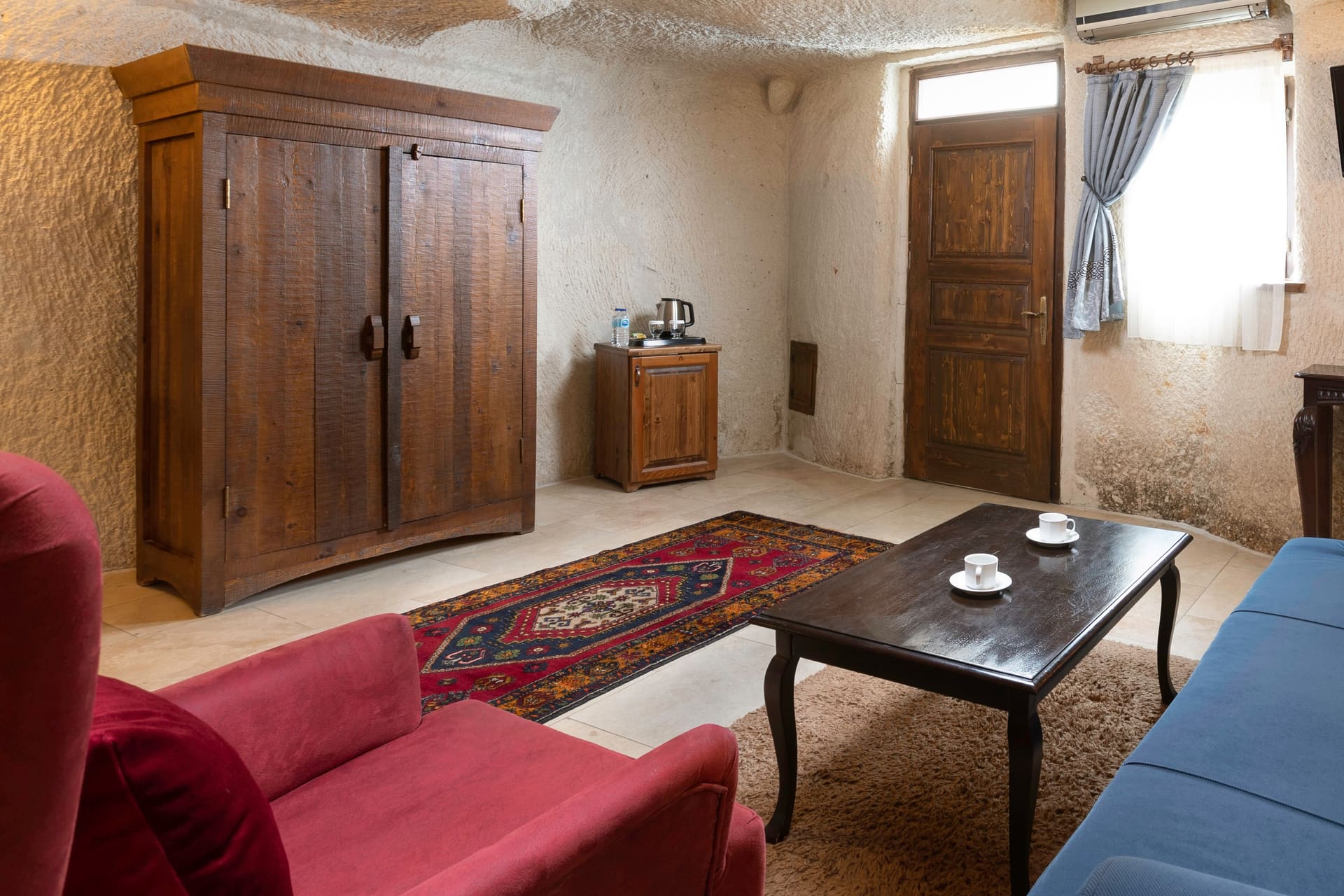 Room 114, Junior Cave Suite: living area, wardrobe, door, blue sofa and coffee table