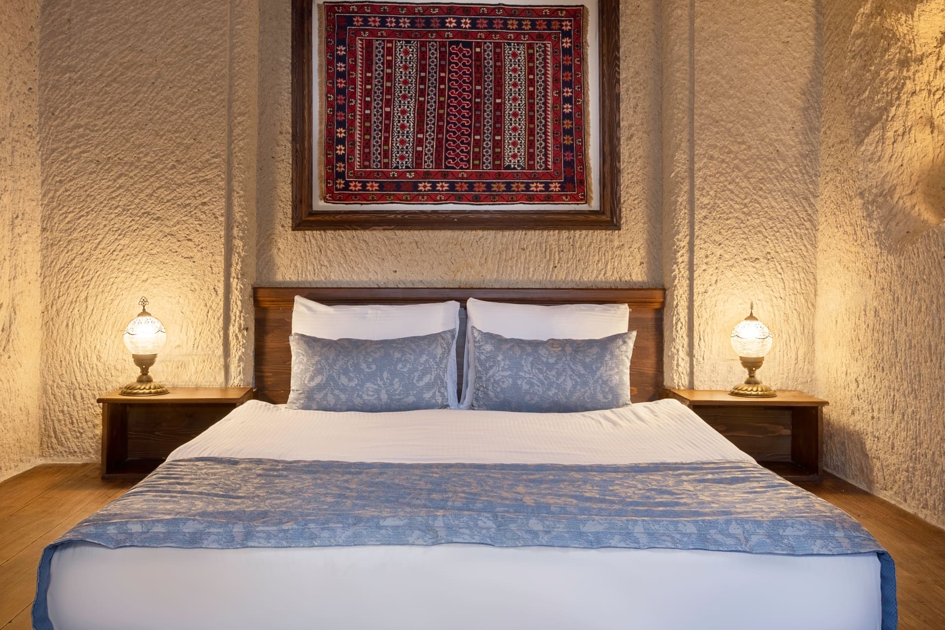 Room 114, Junior Cave Suite: frontal view of the bed, blue pillows, wall art above the headboard