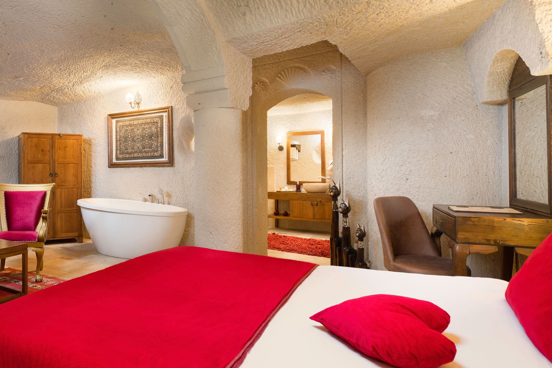 Room 115, Junior Cave Suite: bolster pillow on the bed, wardrobe, bathtub and mirror behind