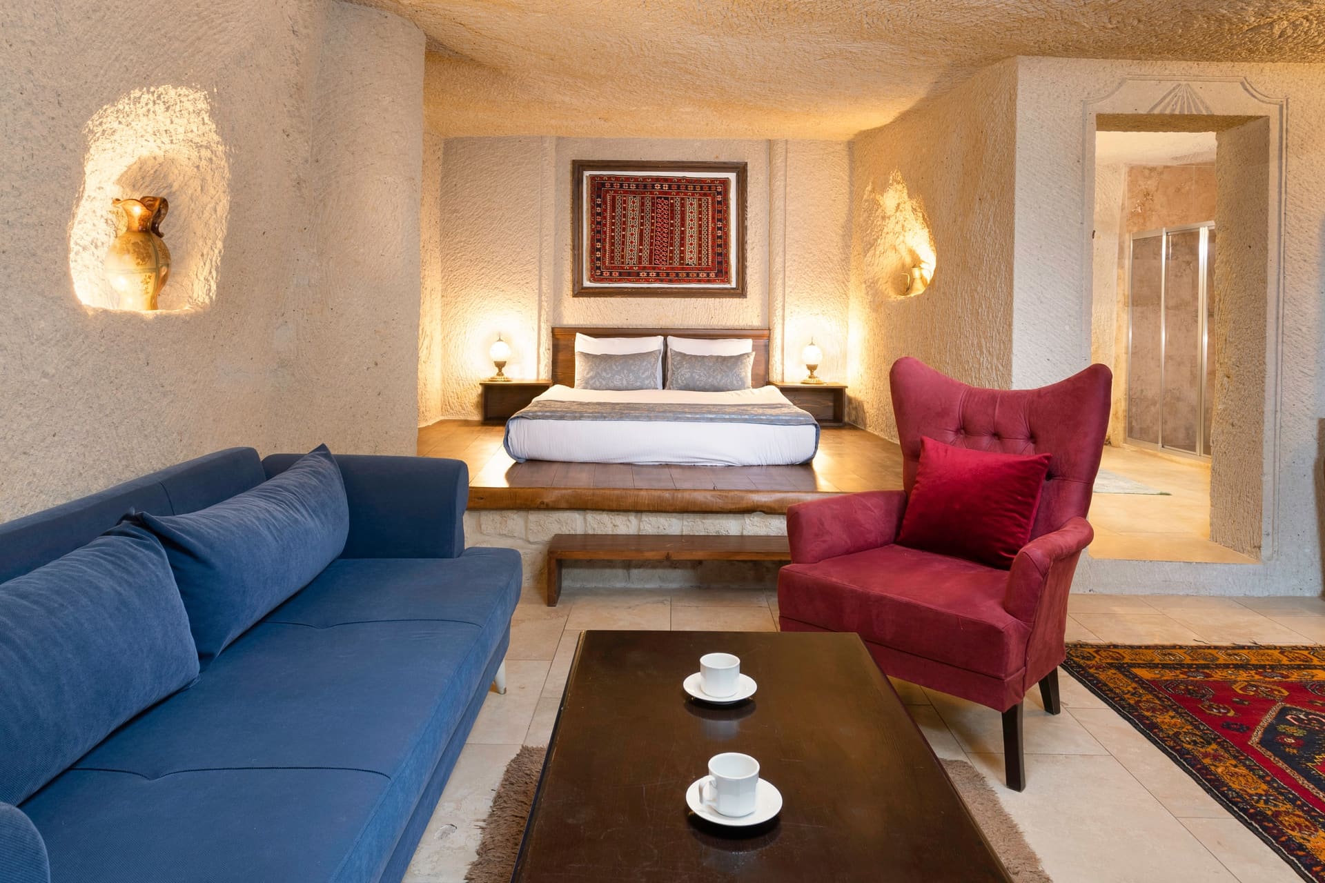 Room 114, Junior Cave Suite: sectional sofa, burgundy armchair, bed alcove and mirror behind