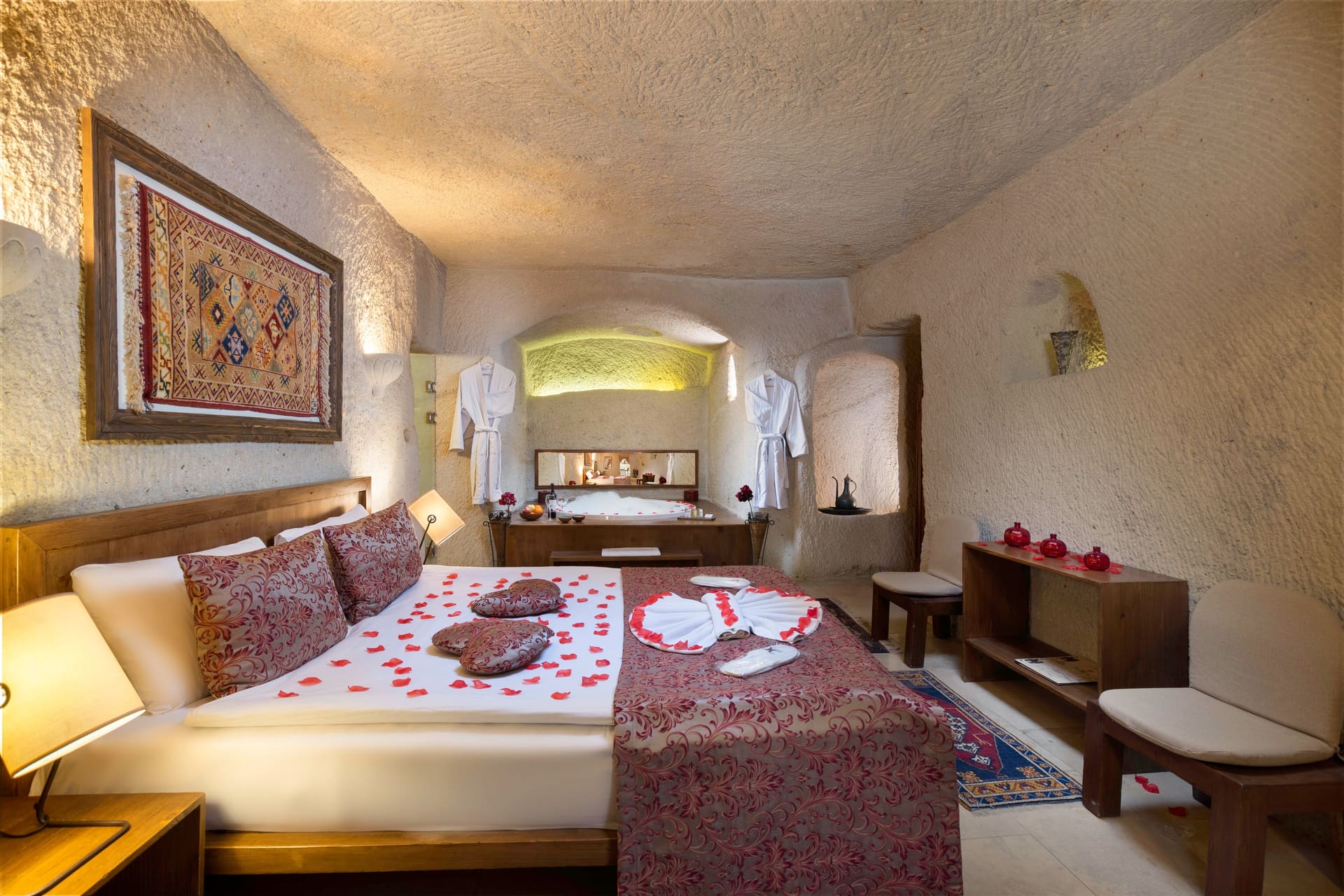 Room 111, King Cave Suite: a swan-folded towel and rose petals on the bed, robes hanging on either side
