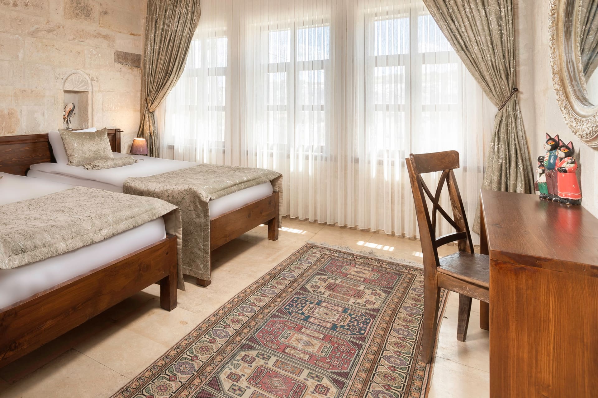 Room 117, Junior Suite: Twin beds, tall curtained windows, wooden chair, rug.