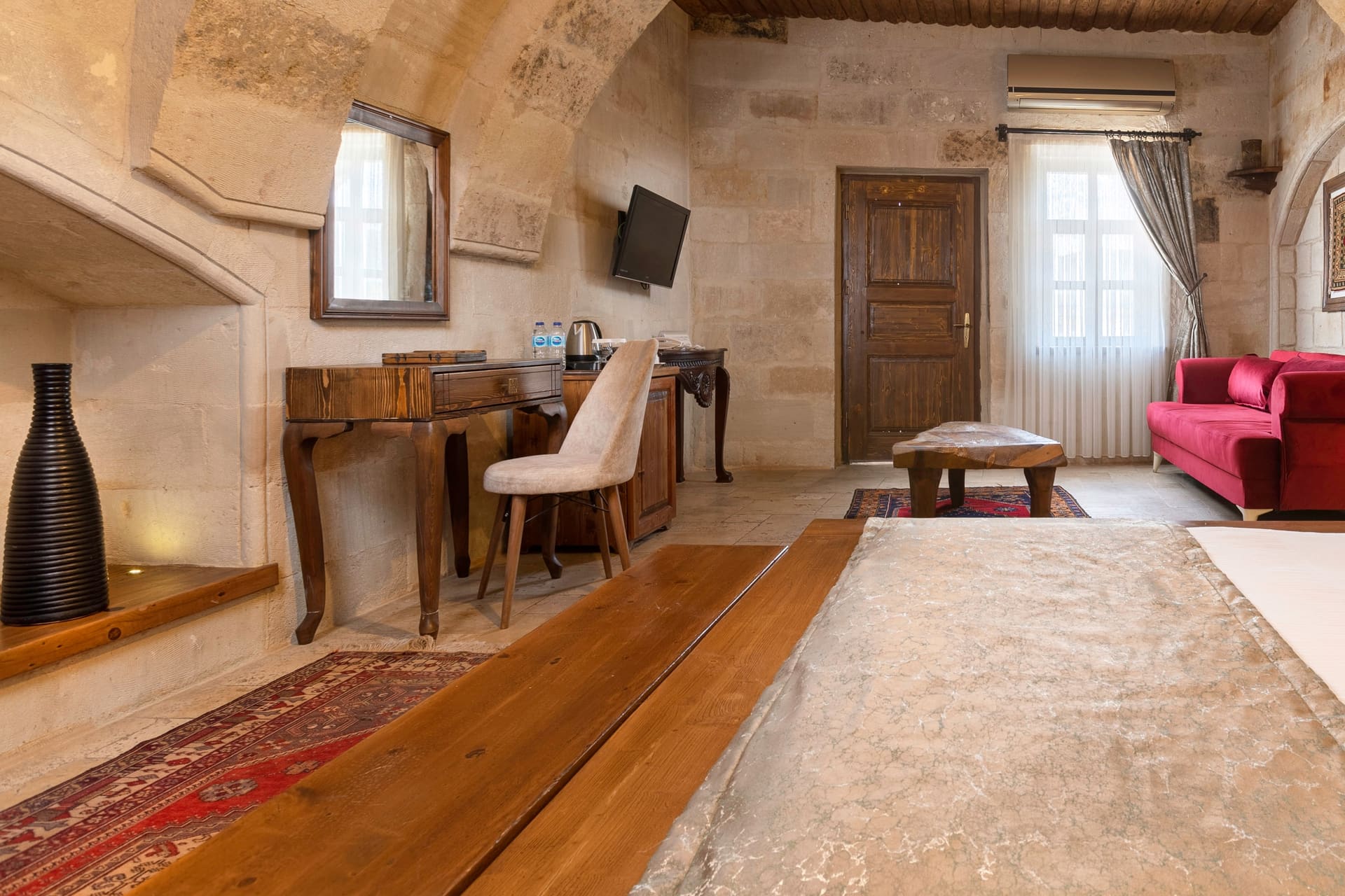 Room 108, Junior Suite: Seating corner, desk, TV, wooden door, window.