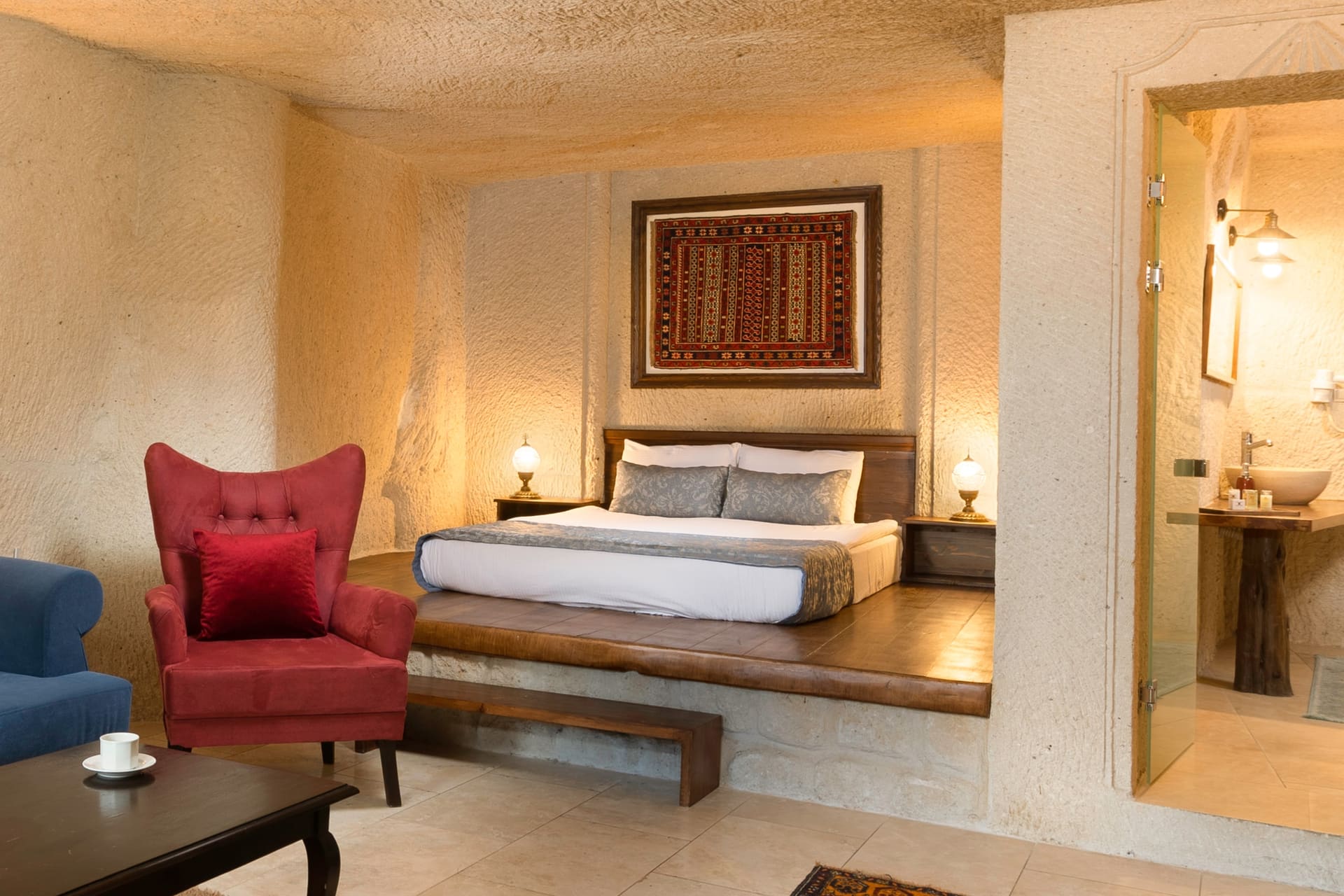 Room 114, Junior Cave Suite: bed set in a stone alcove, blue sofa in front, bathroom door visible