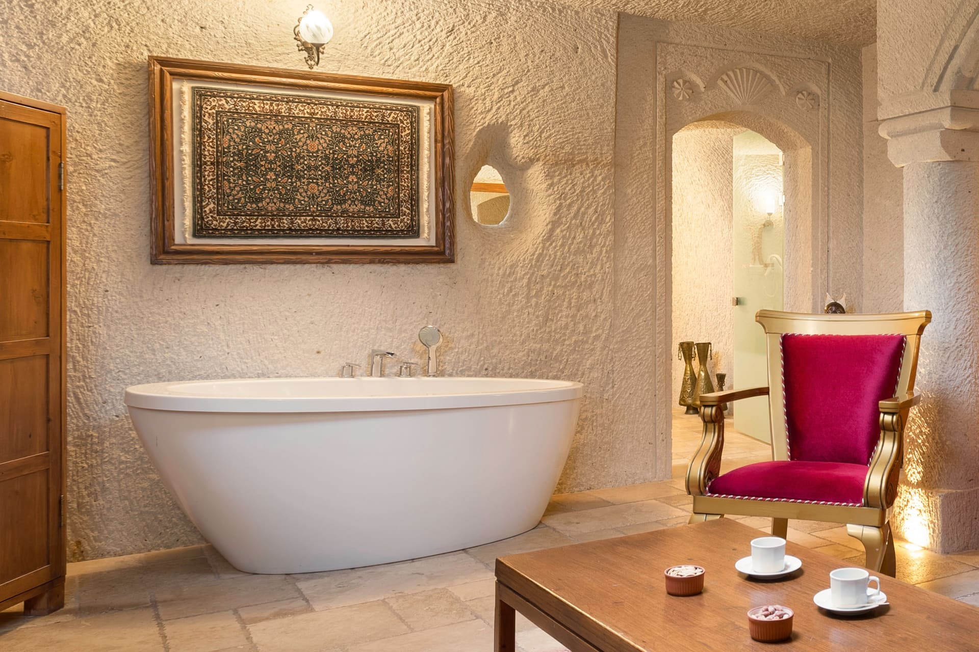 Room 115, Junior Cave Suite: close view of the bathtub, burgundy chair, arched stone wall