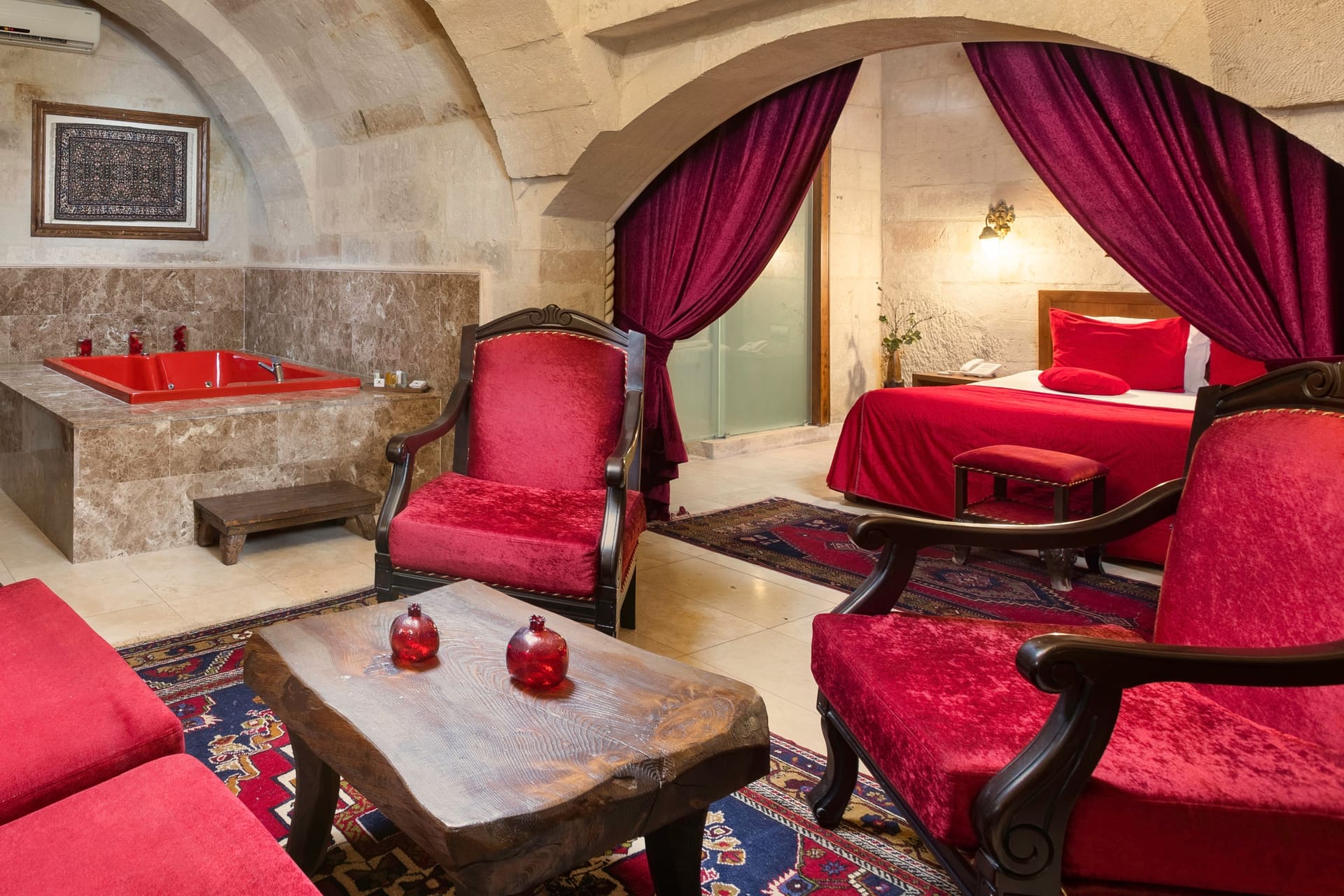 Room 110, Queen Suite: Jacuzzi and armchairs in the foreground, the bed visible behind.