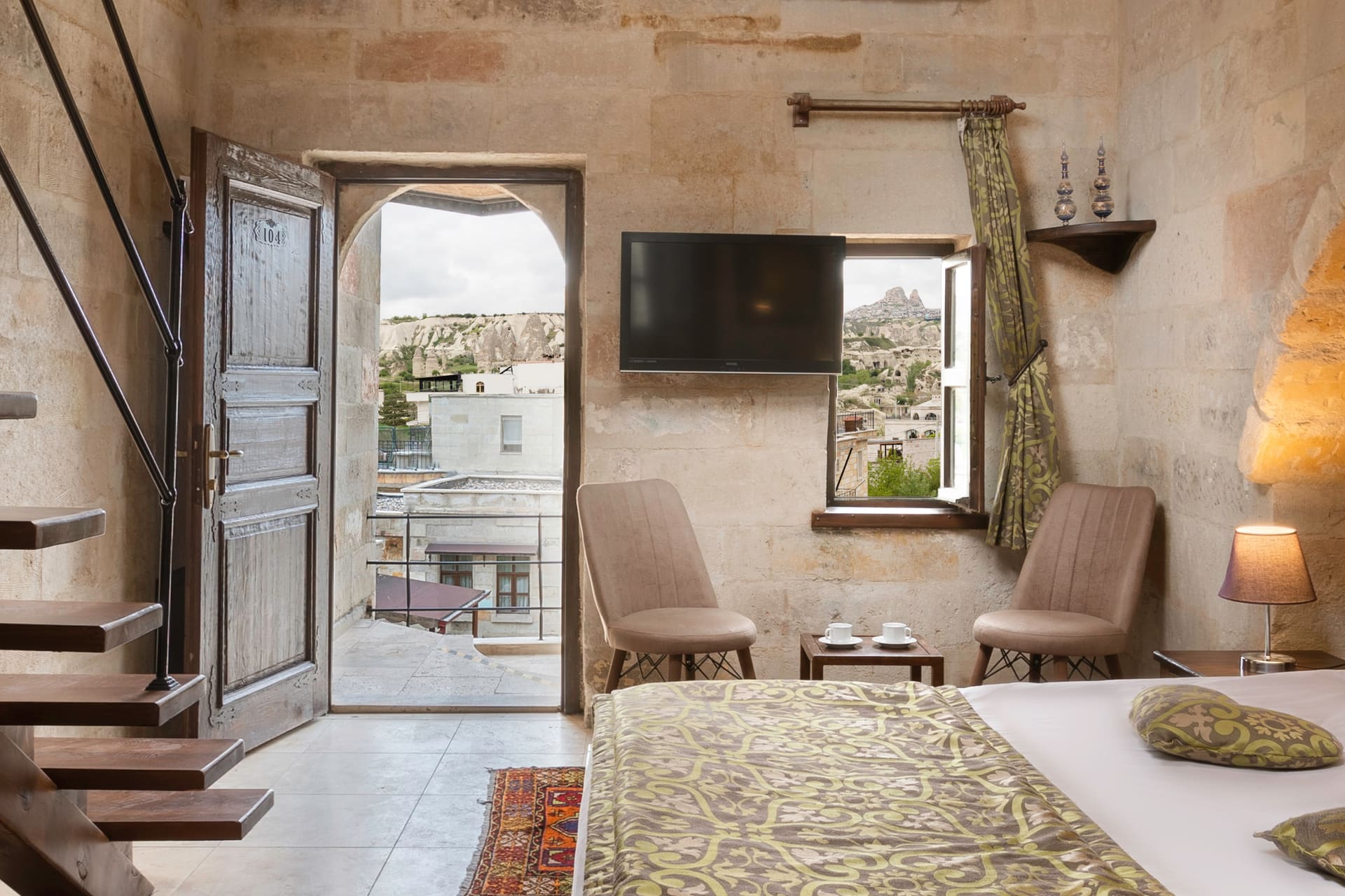 Room 104, Junior Suite: Wooden door open to balcony, armchairs, table, curtained window.