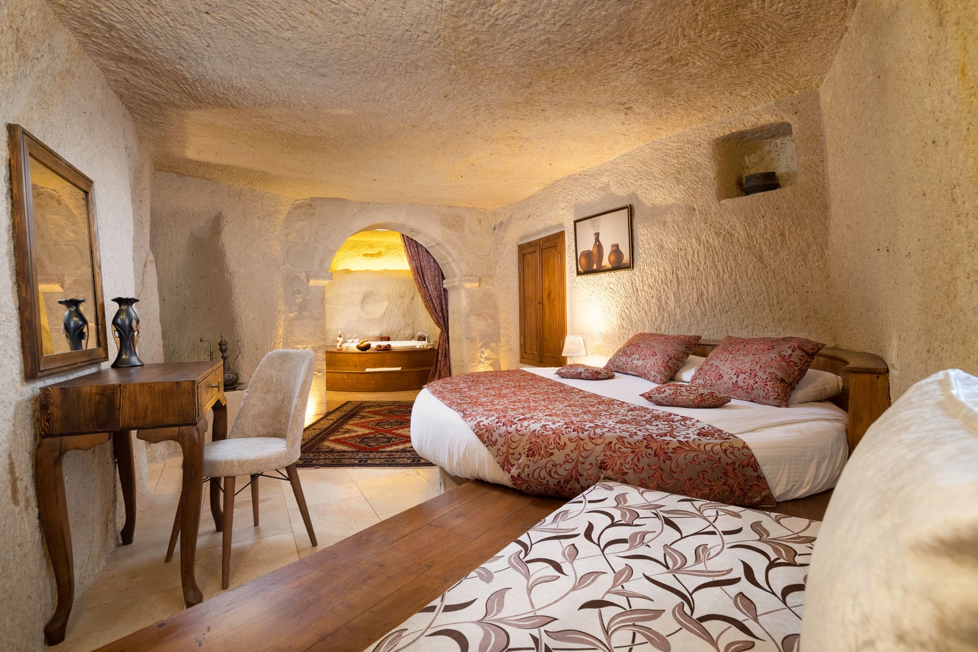 Room 112, King Cave Suite: the bed with a small bathroom niche and a wooden door visible behind it