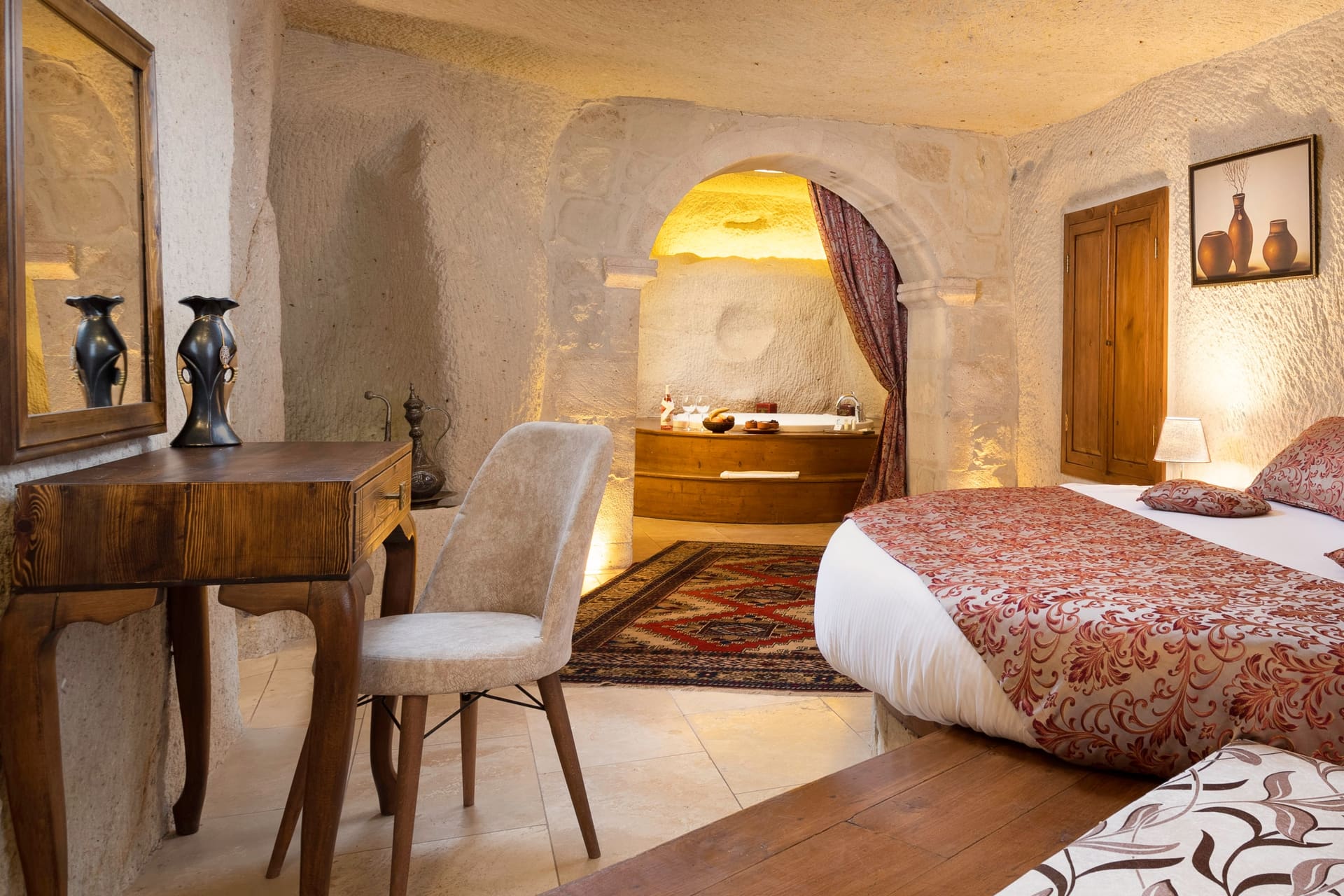 Room 112, King Cave Suite: a dressing table with mirror and chair, the jacuzzi niche behind, the bed alongside
