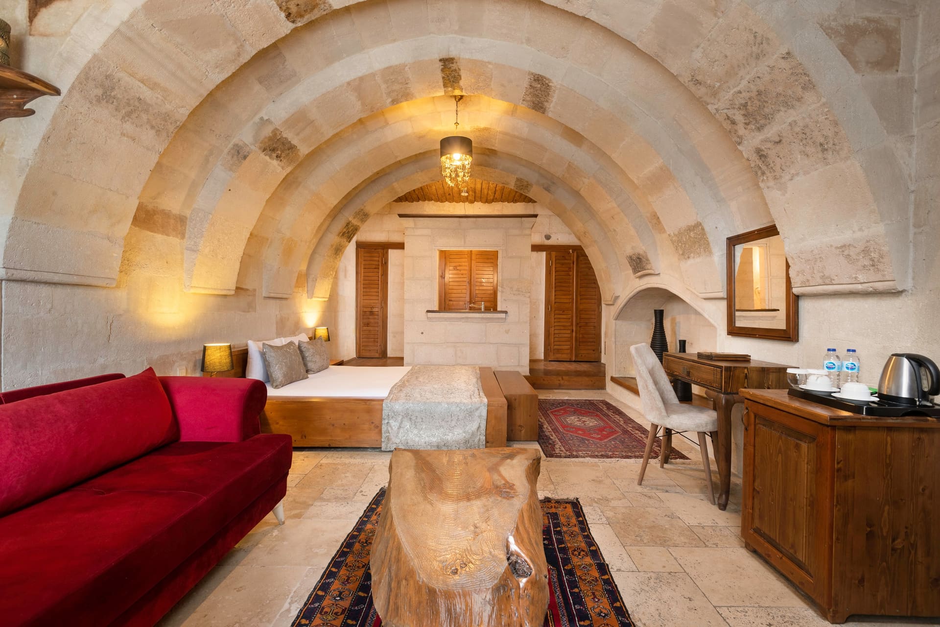Room 108, Junior Suite: Double bed, red sofa and rugs under an arched stone ceiling