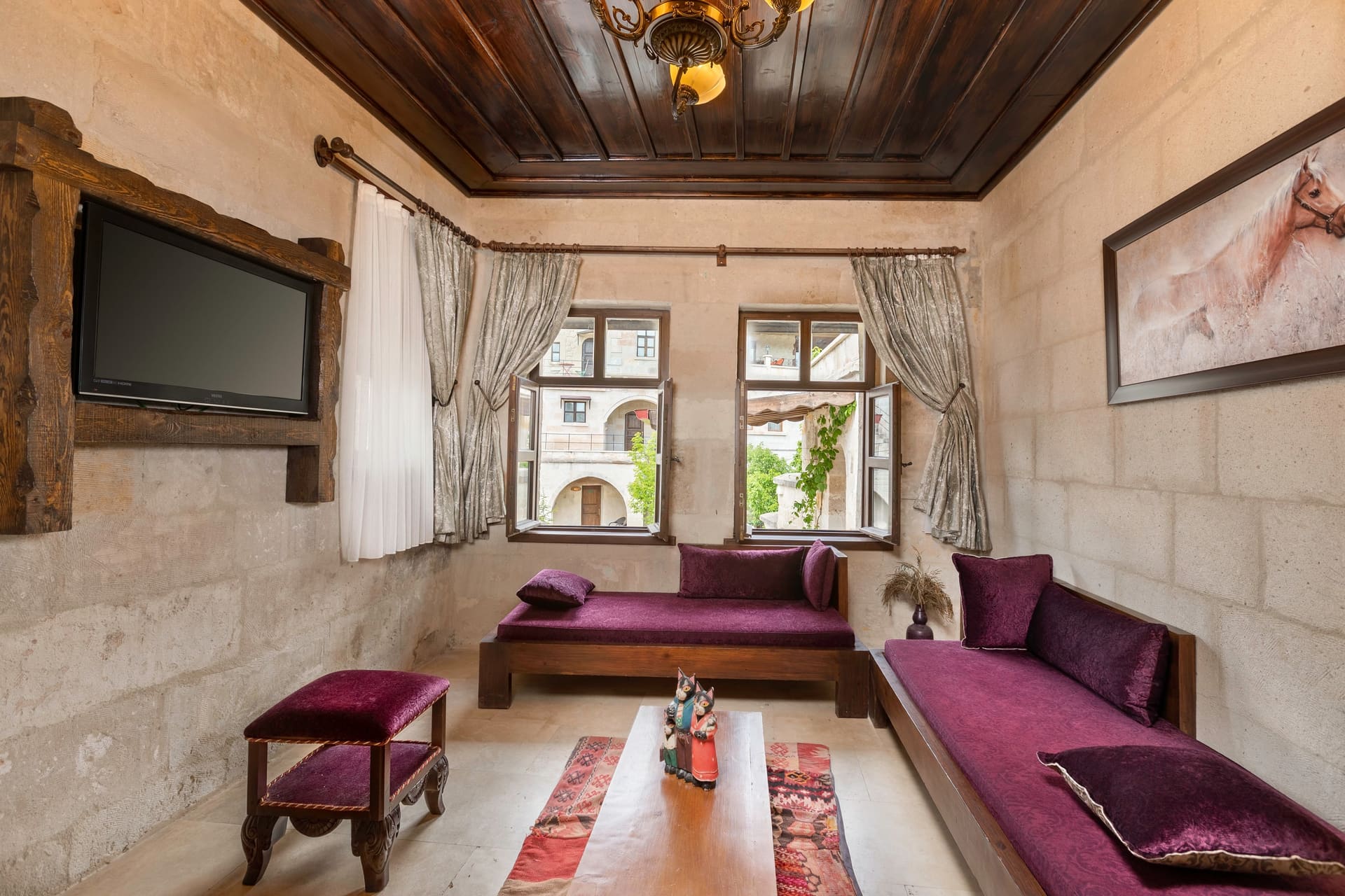 Room 117, Junior Suite: Seating area, wall-mounted TV, purple sofas, arched windows.