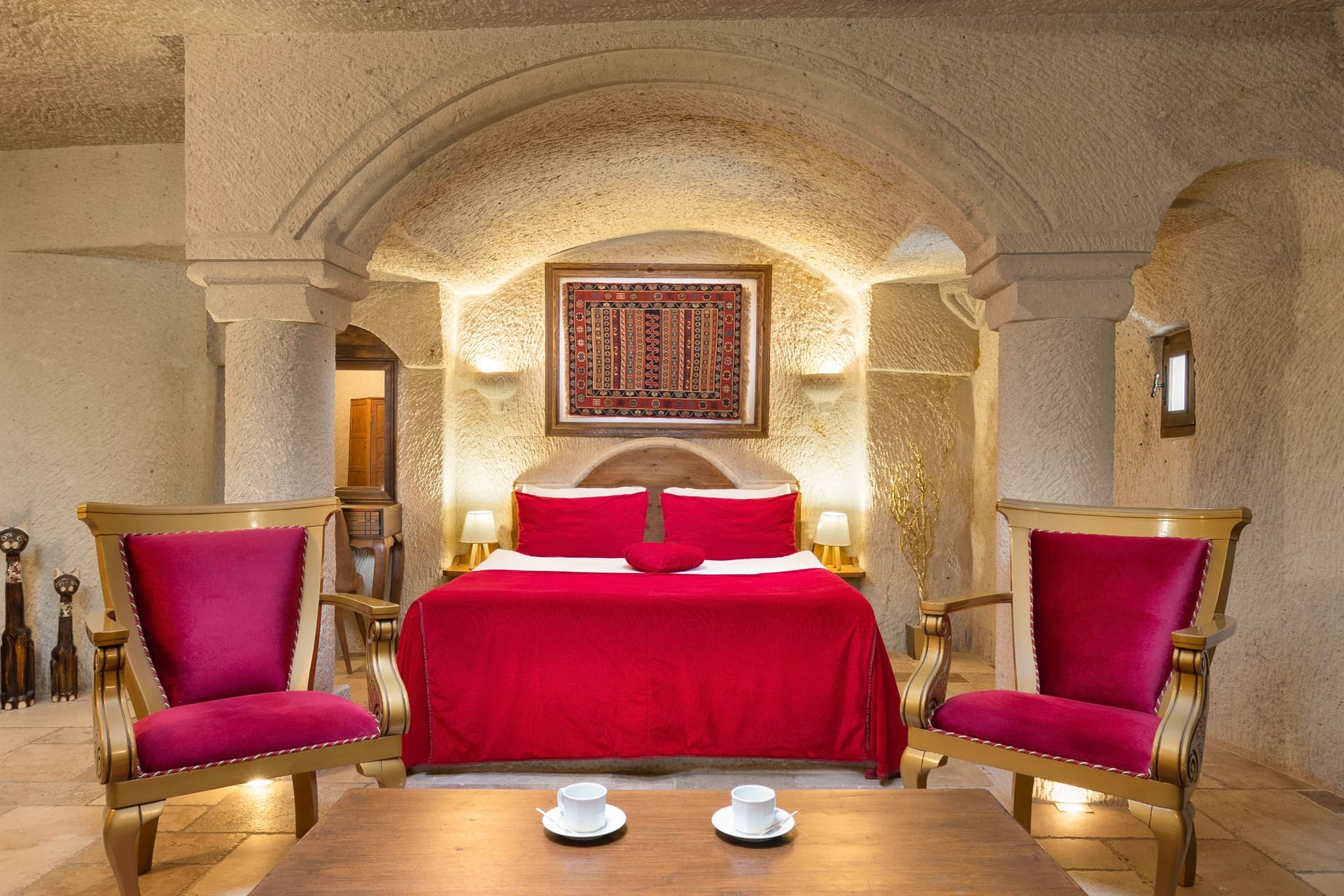Room 115, Junior Cave Suite: burgundy chairs on either side of the bed, wall art above the headboard