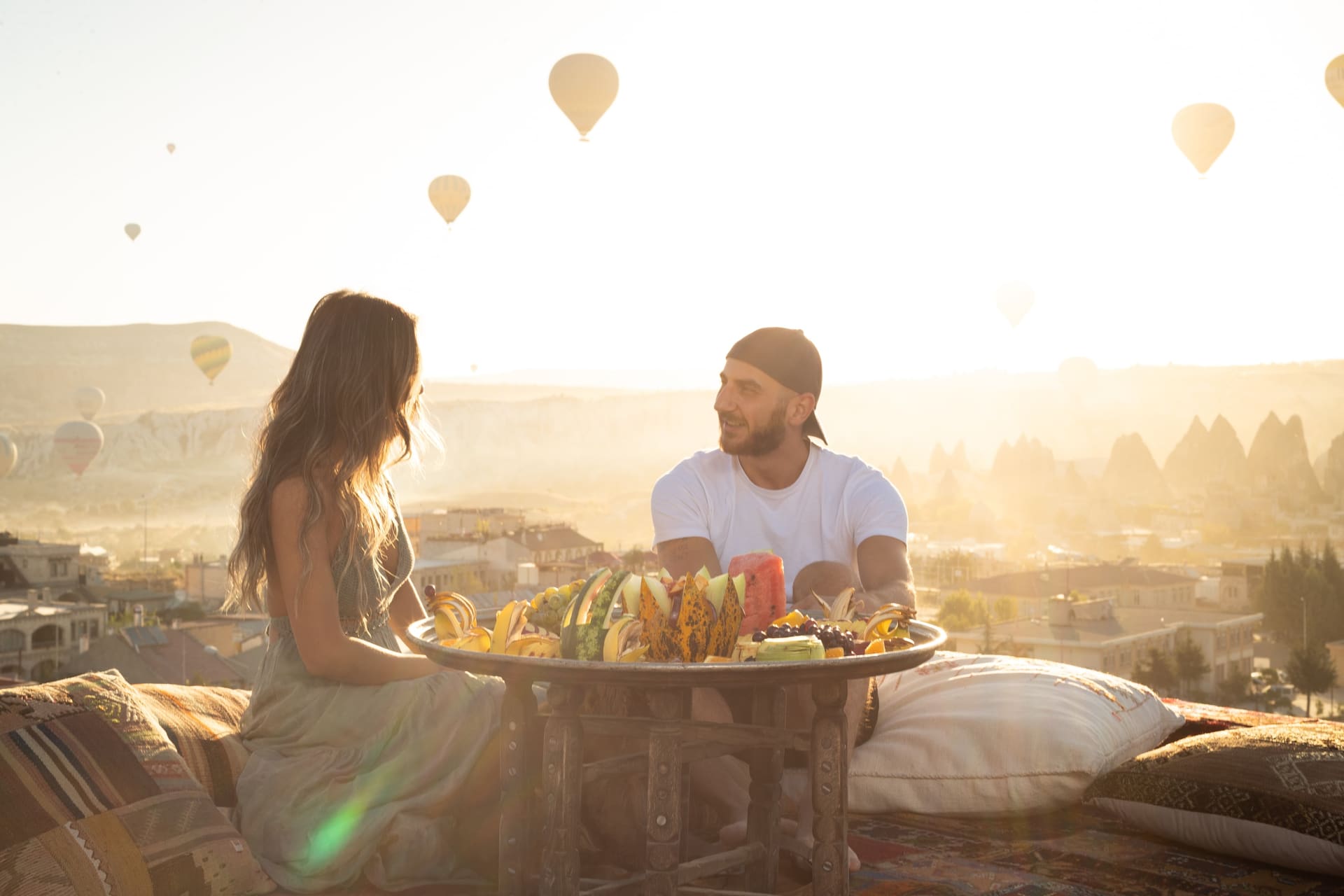 Couple at a breakfast table with a wide valley view and balloons nearby