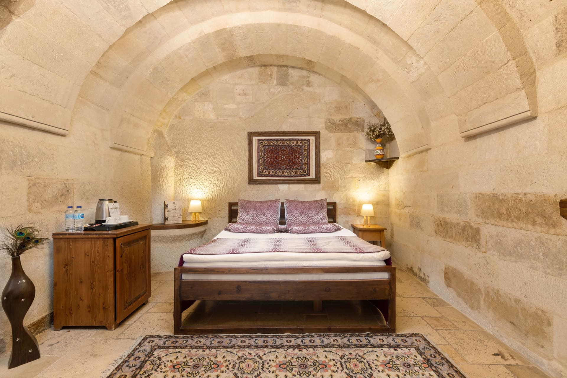 Room 109, Deluxe: Bed beneath a vaulted stone ceiling, framed artwork above
