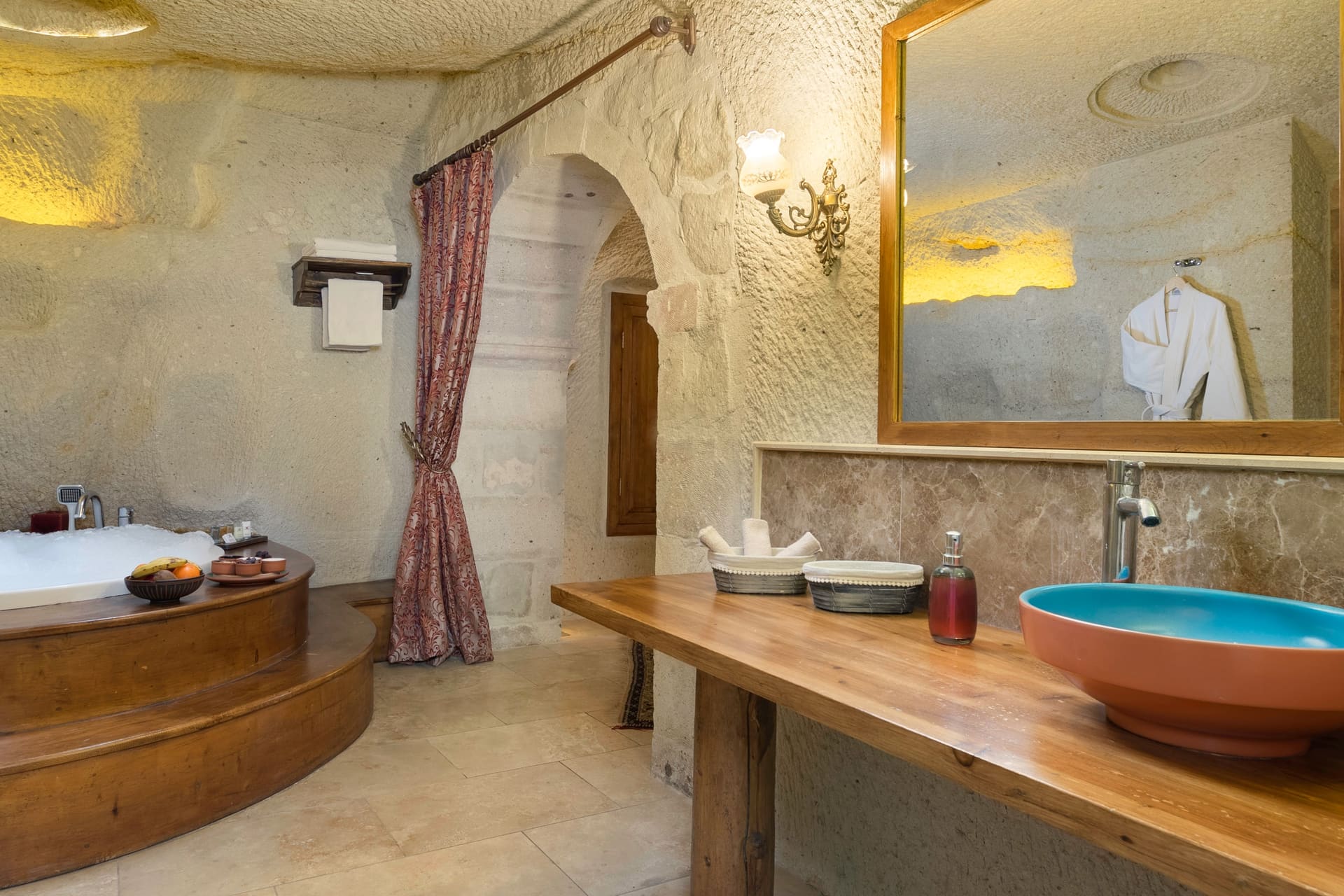 Room 112, King Cave Suite: the jacuzzi tub with steps, the sink counter to the right, an arched door and curtain