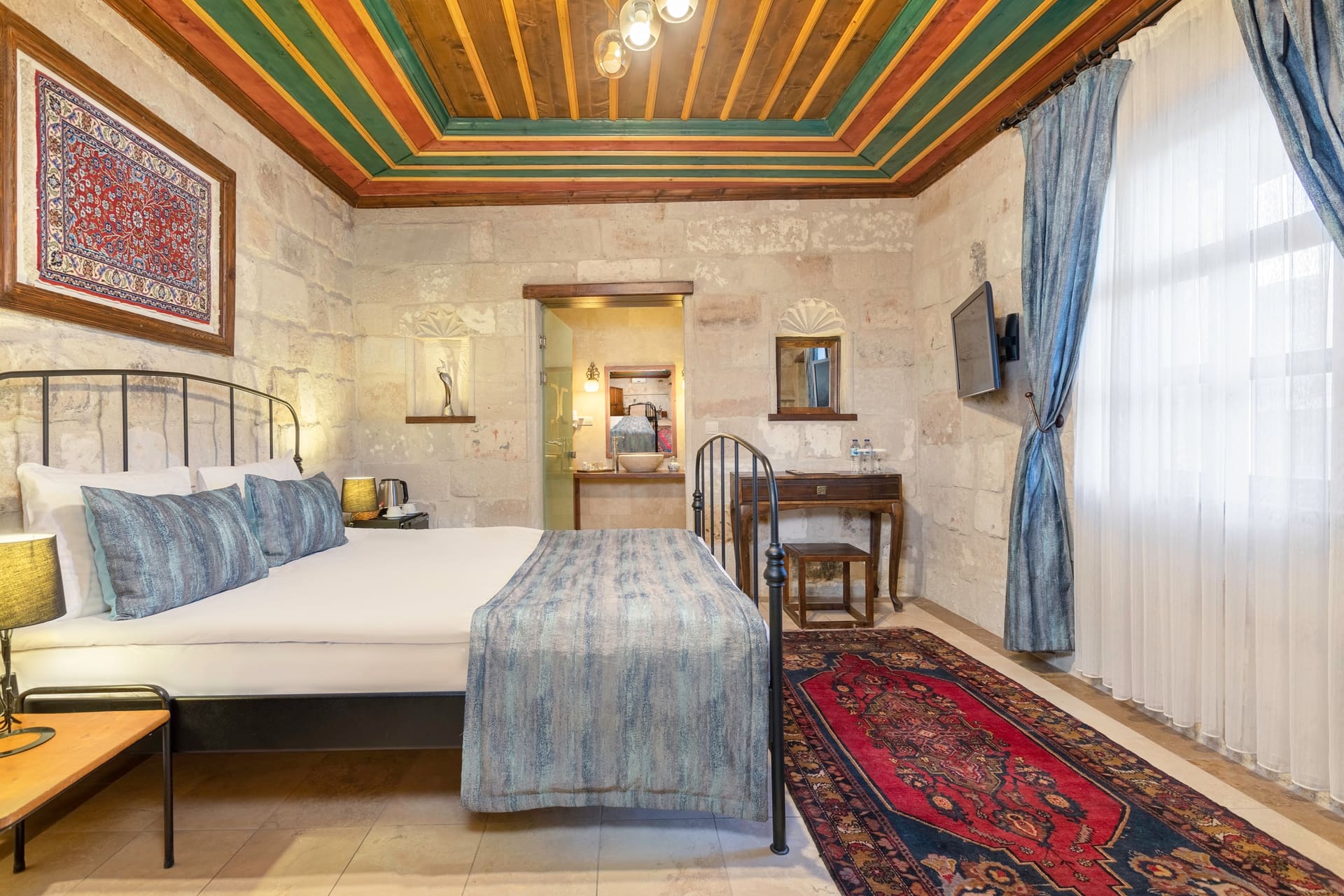 Room 101, Deluxe: Bed with a small side table, wall-mounted television