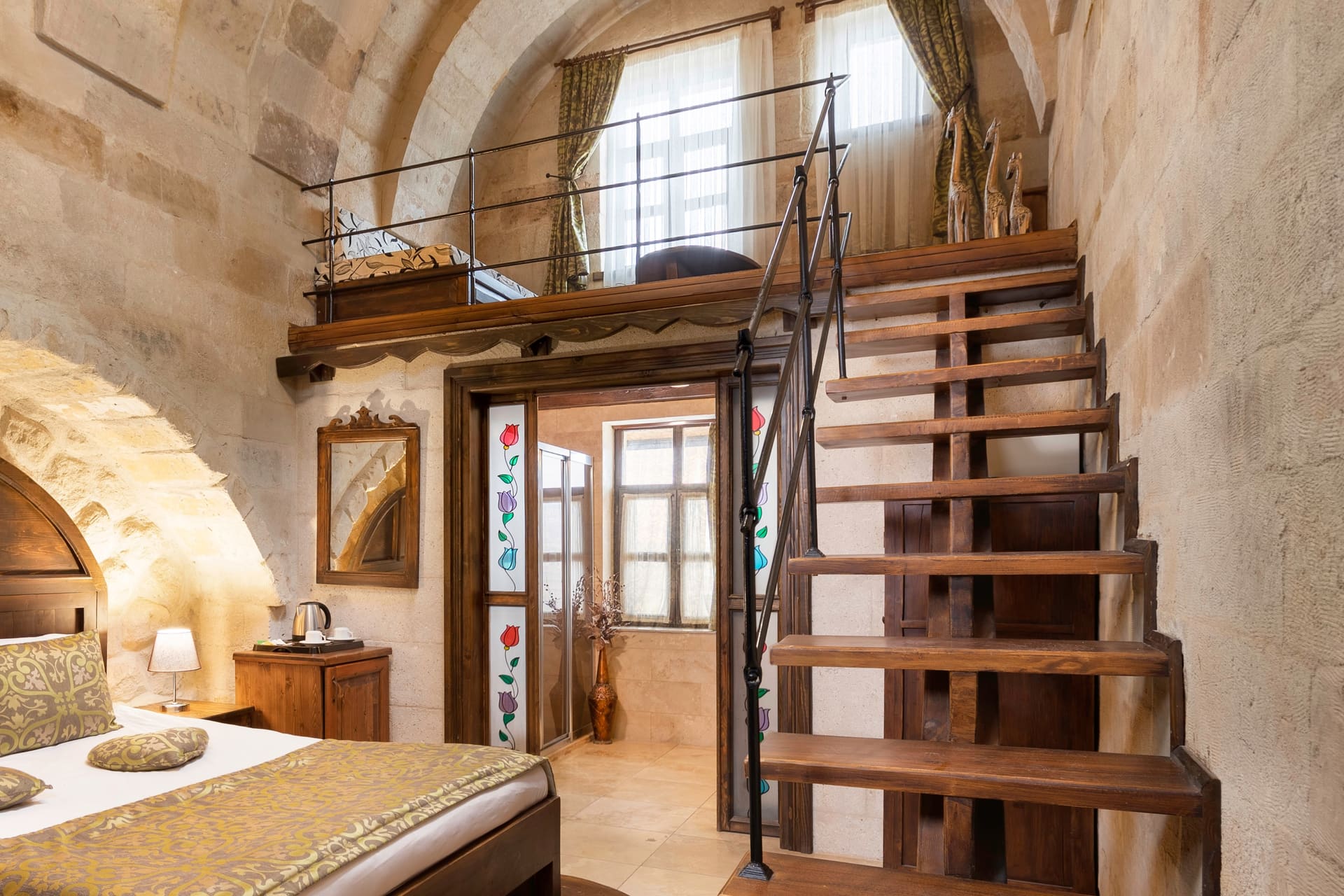 Room 104, Junior Suite: Arched bed alcove, staircase, mirror, patterned bedspread.
