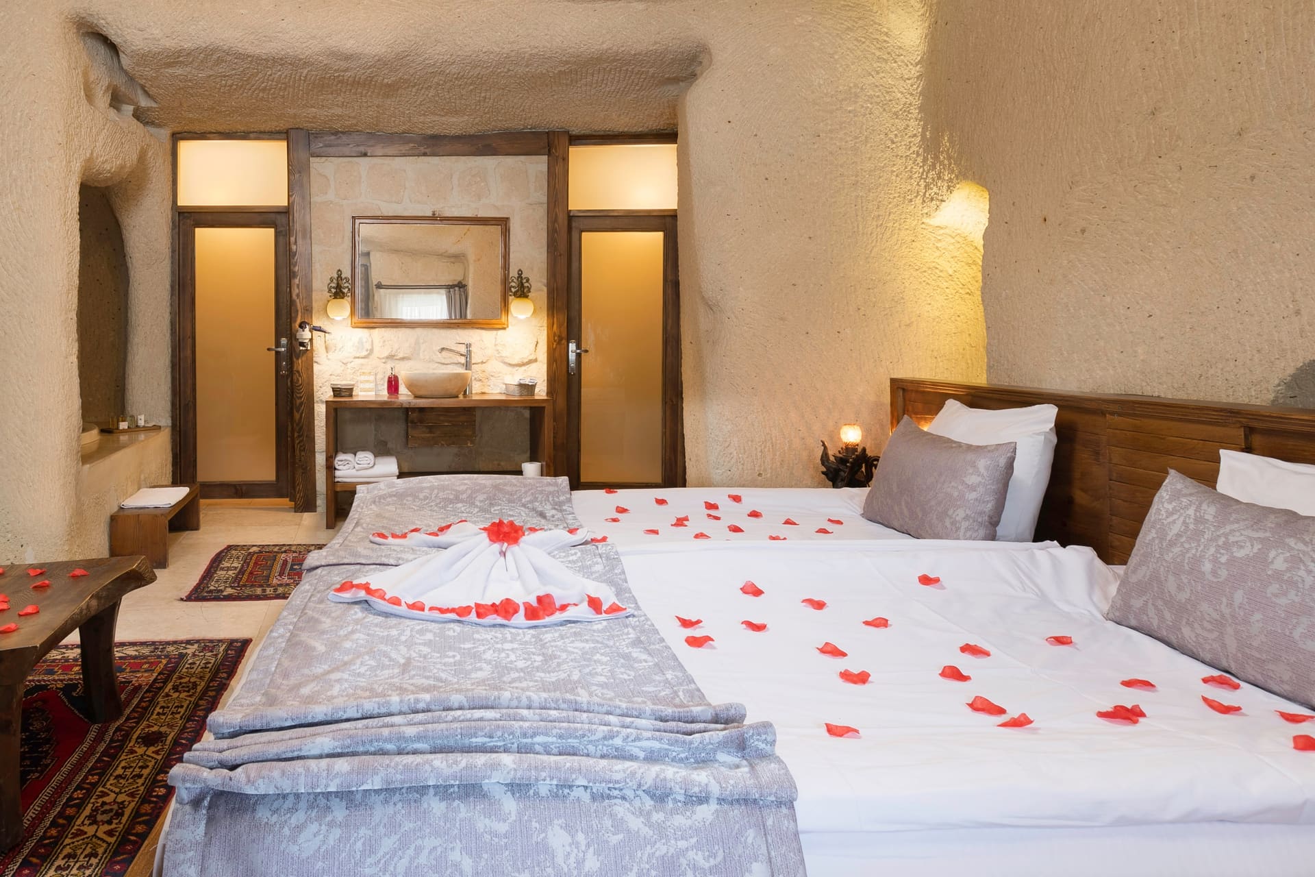 Room 113, Junior Cave Suite: close view of the bed with scattered rose petals, mirror behind