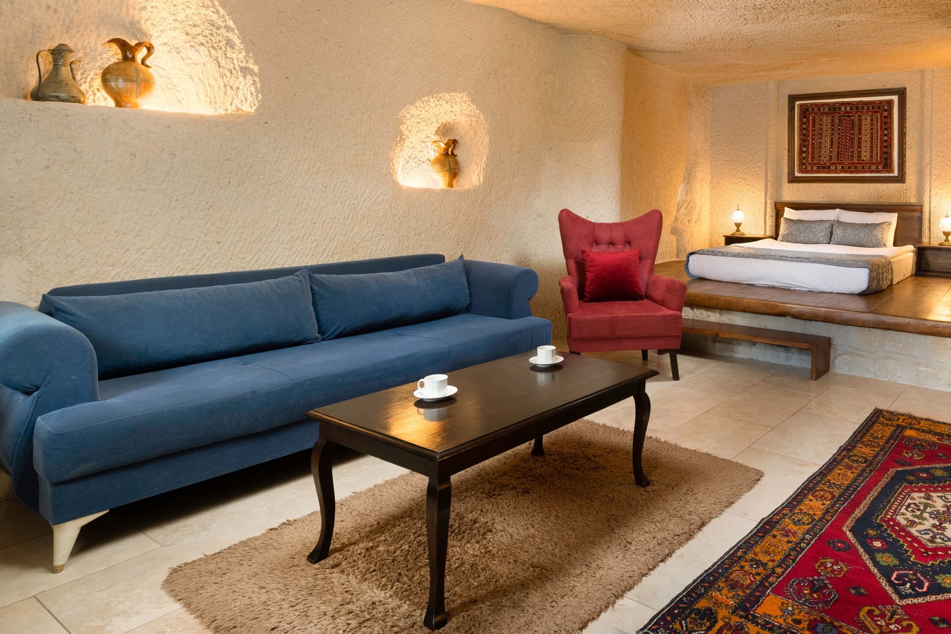 Room 114, Junior Cave Suite: blue sofa and burgundy armchair, coffee table, bed alcove in the background