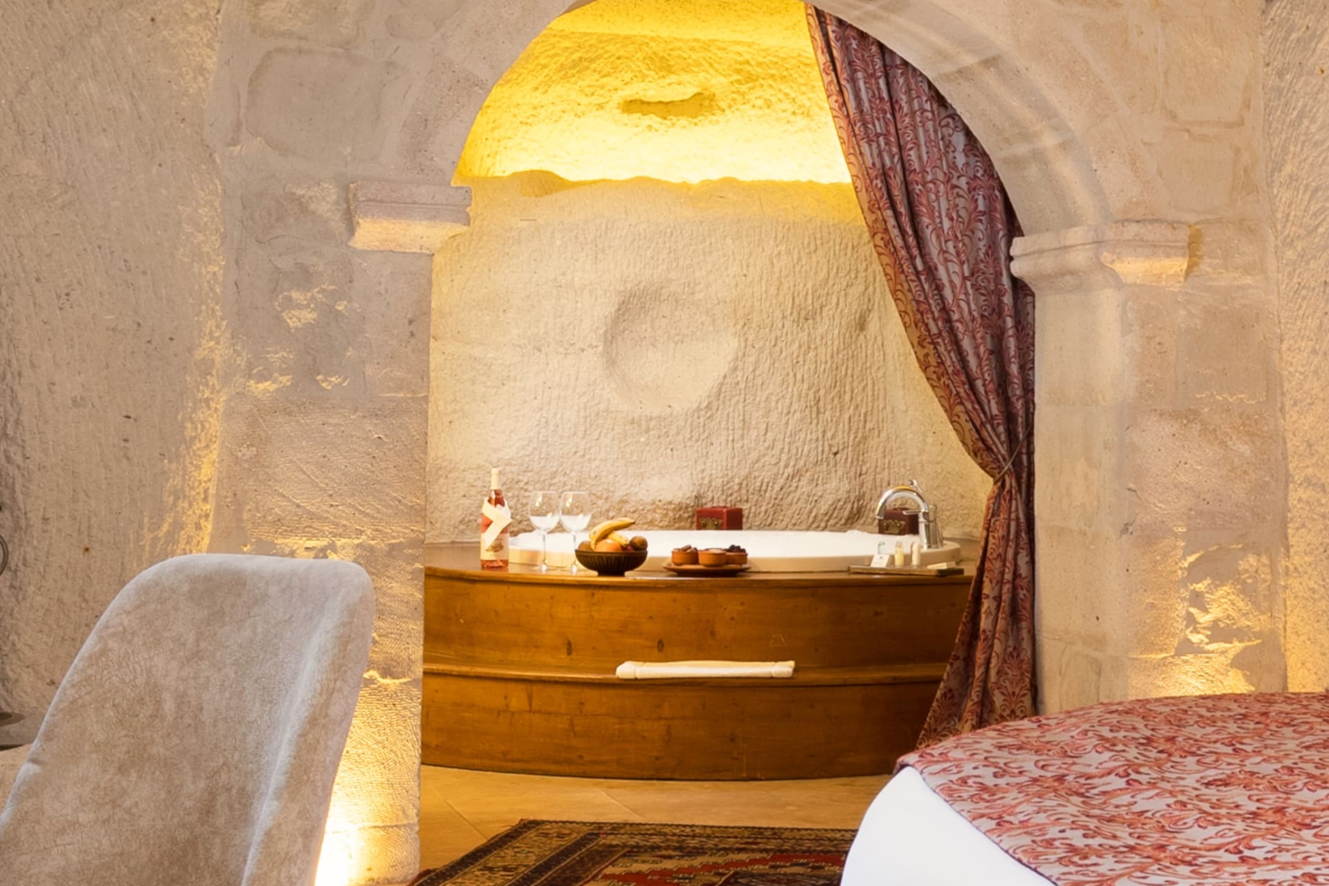 Room 112, King Cave Suite: view through the arch showing the jacuzzi tub, a wine bottle, and a fruit bowl