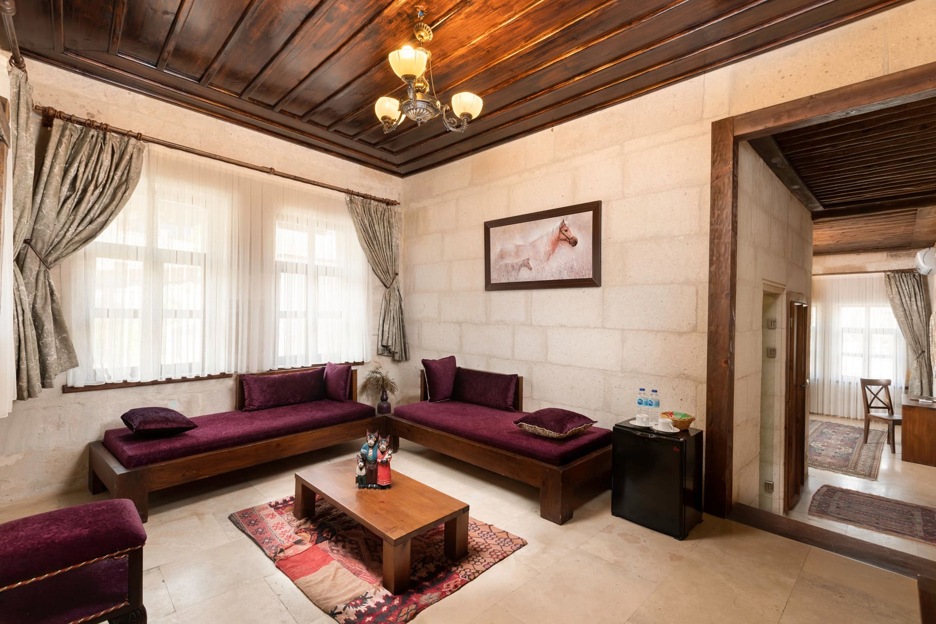 Room 117, Junior Suite: Seating area, purple sofas, coffee table, wood-beamed ceiling.