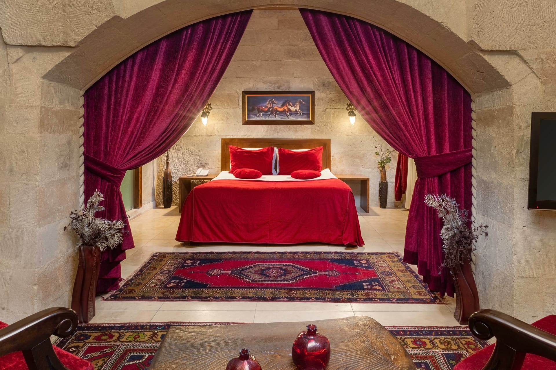 Room 110, Queen Suite: Red-draped bed in a stone alcove with red curtains and a painting above the headboard.