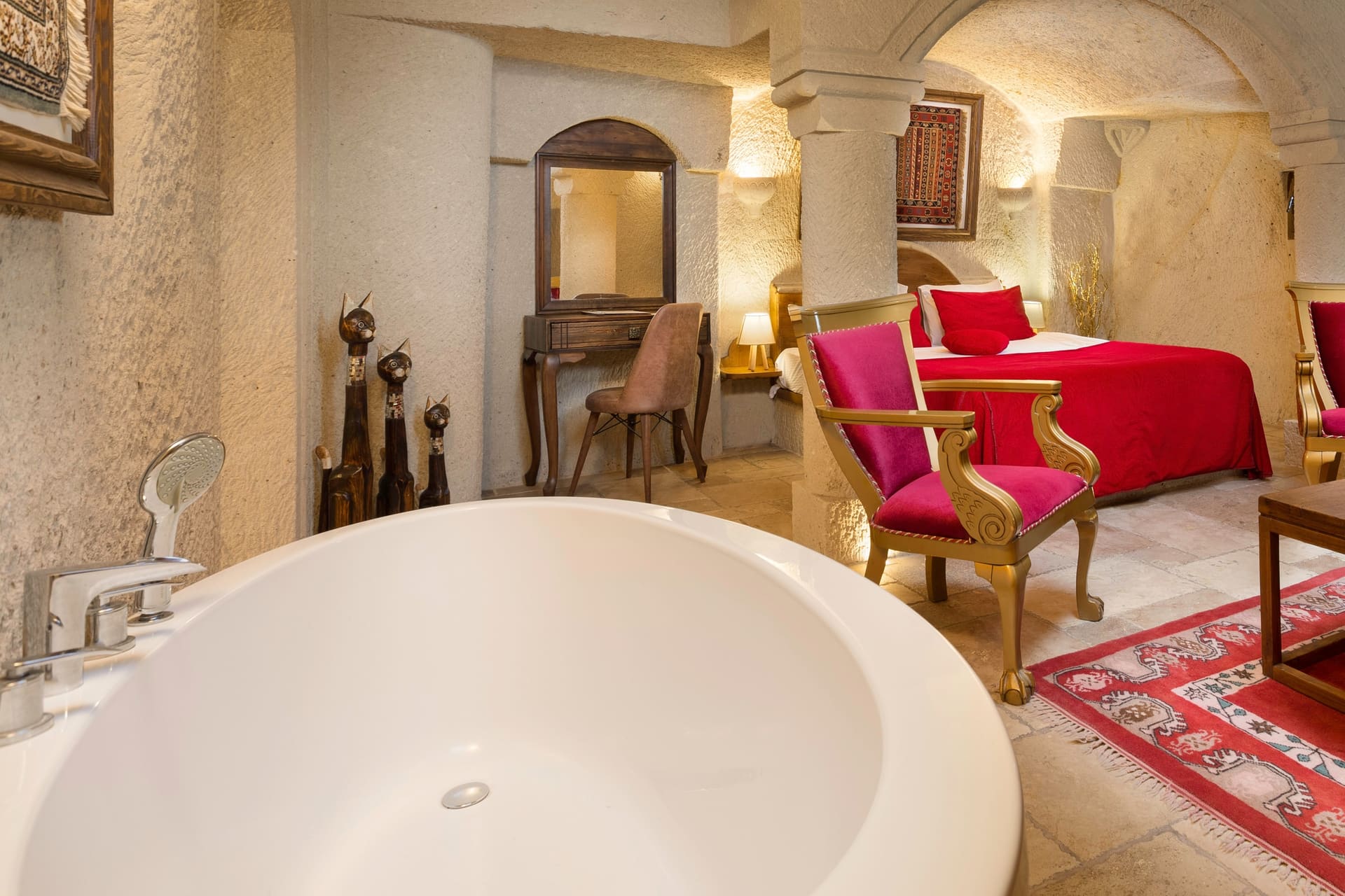Room 115, Junior Cave Suite: bathtub and burgundy chair, mirrored dressing table behind