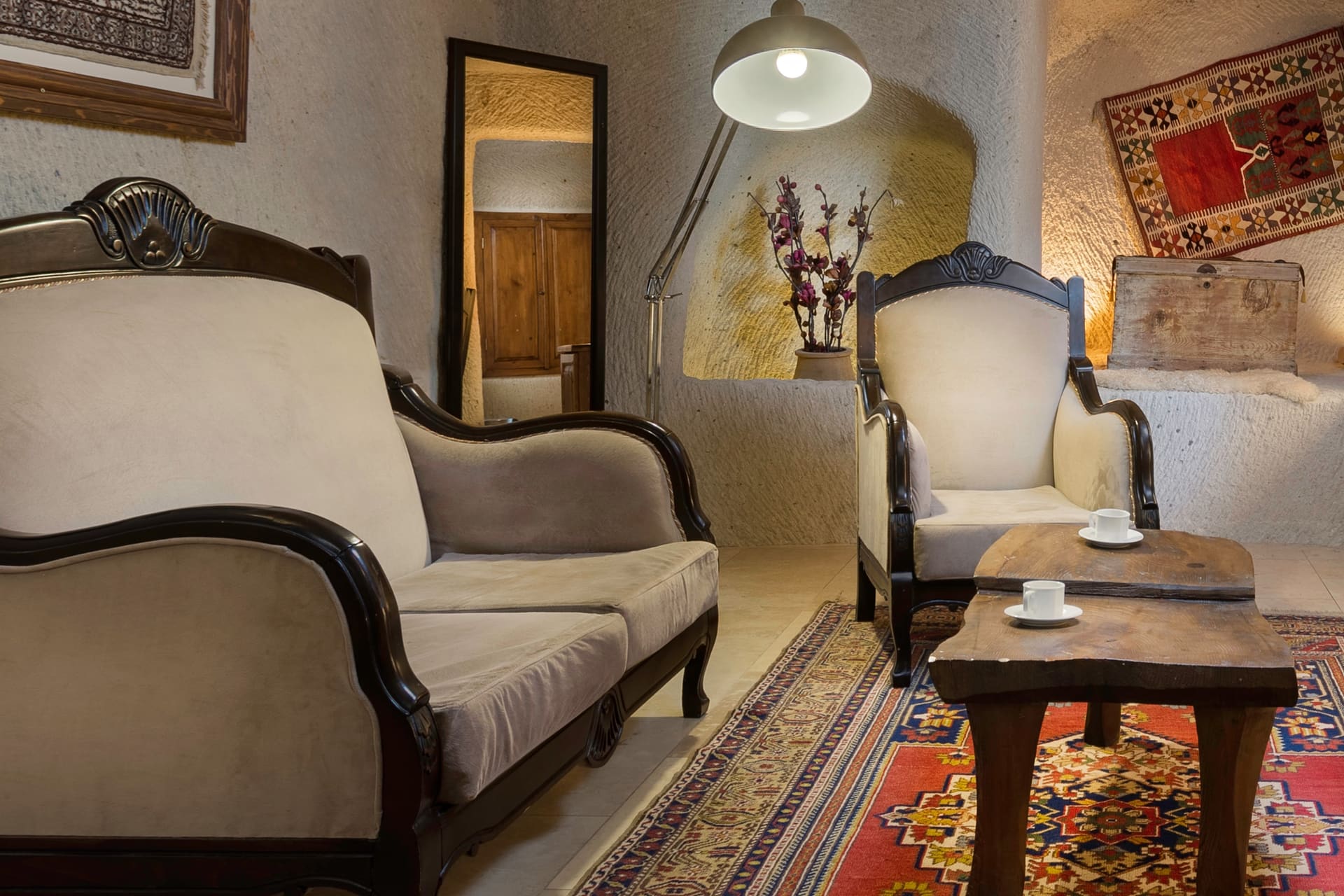 Room 112, King Cave Suite: the loveseat and armchair, a mirrored corner, a floor lamp, and a wall carpet