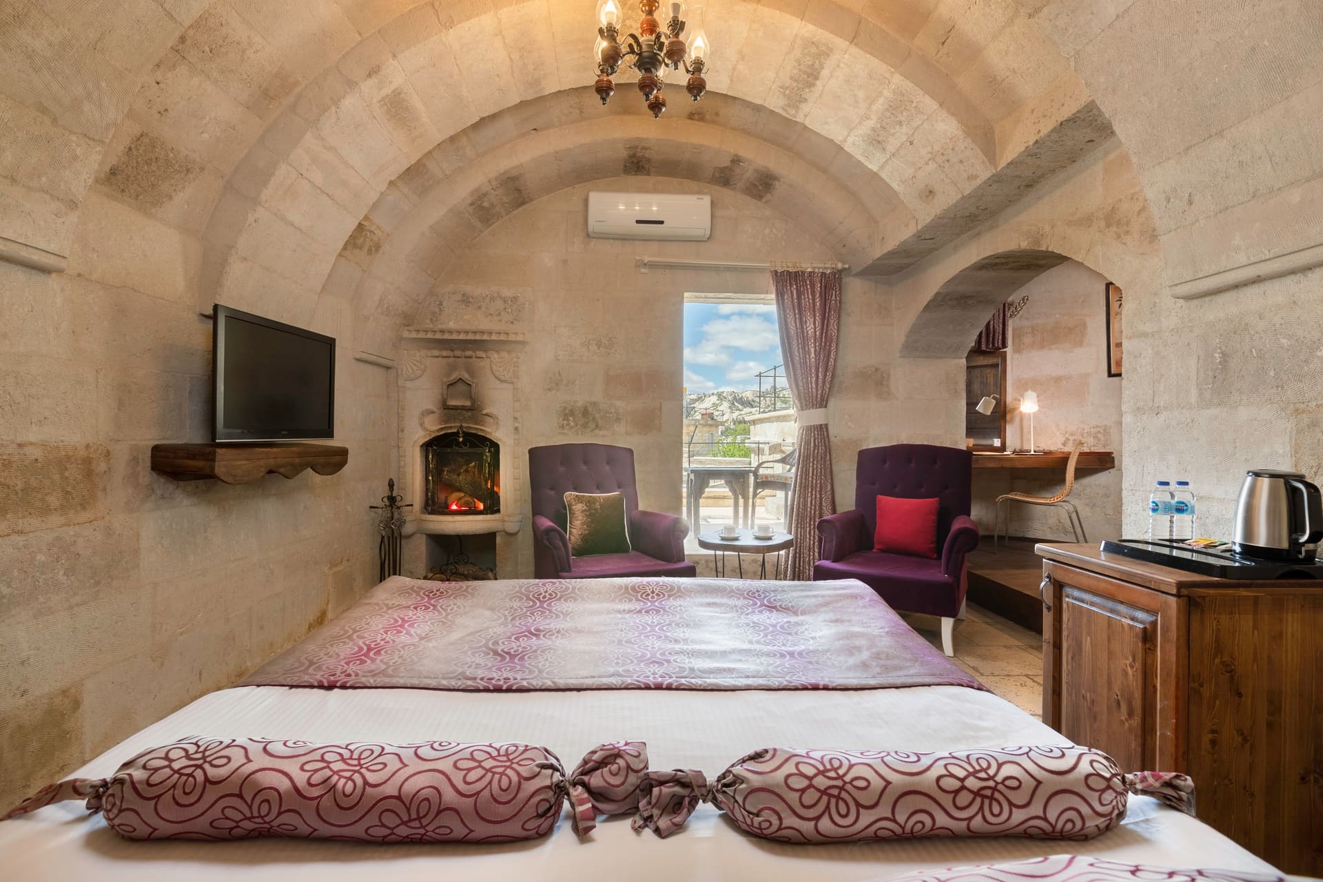 Room 109, Deluxe: Bed with purple pillows, wall-mounted television, fireplace, air conditioning