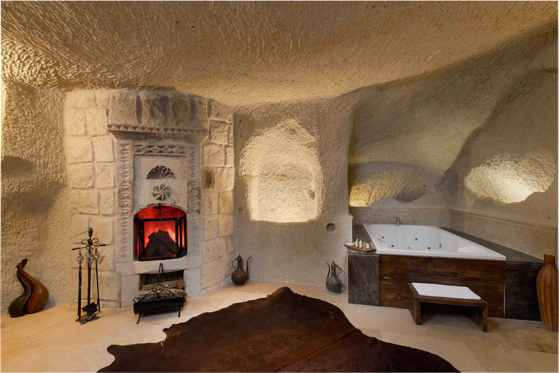 Room 106, King Cave Suite: the lit fireplace next to the jacuzzi tub, a cowhide rug on the floor