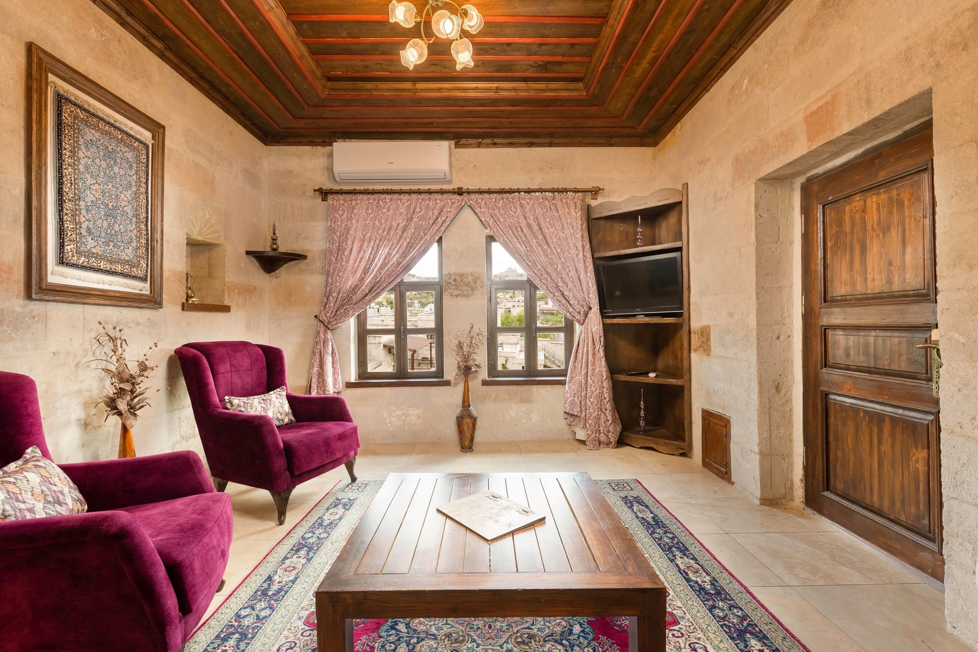 Room 105, King Suite: the stone sitting area with two purple armchairs, a wooden chest and arched windows