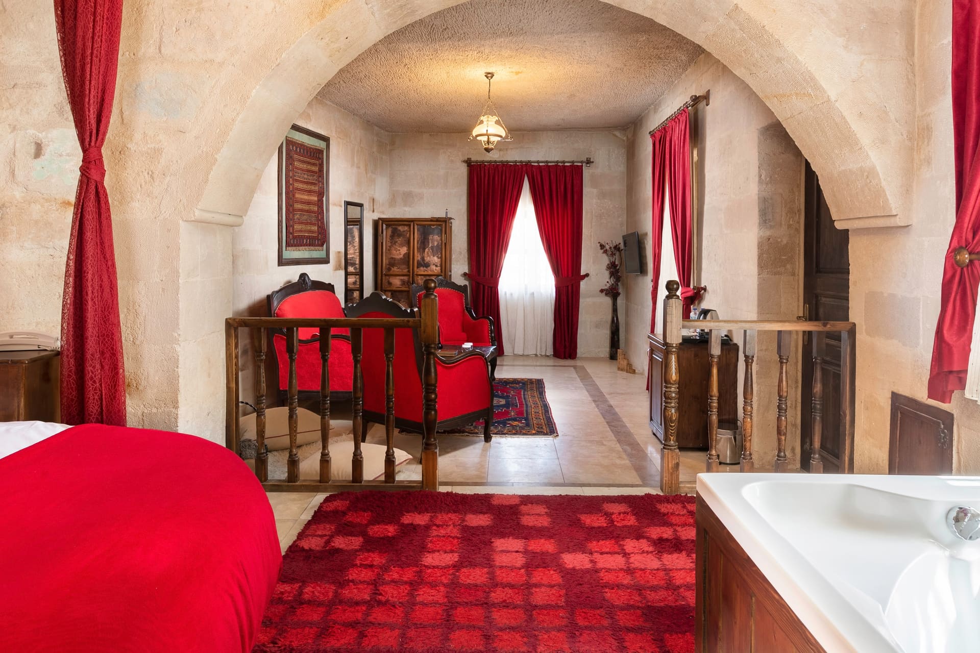 Room 107, King Suite: view through the arched doorway into the sitting corner with a red armchair and curtain