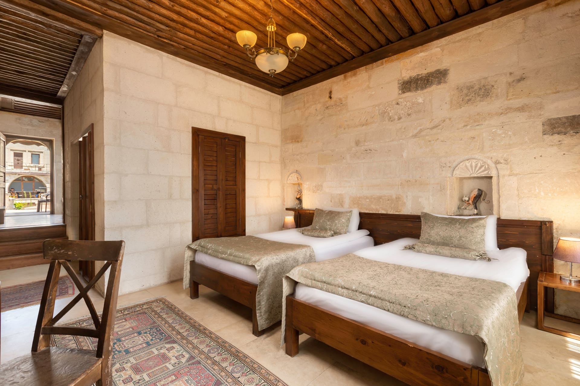 Room 117, Junior Suite: Twin beds, curtained window, courtyard view, wooden chair.