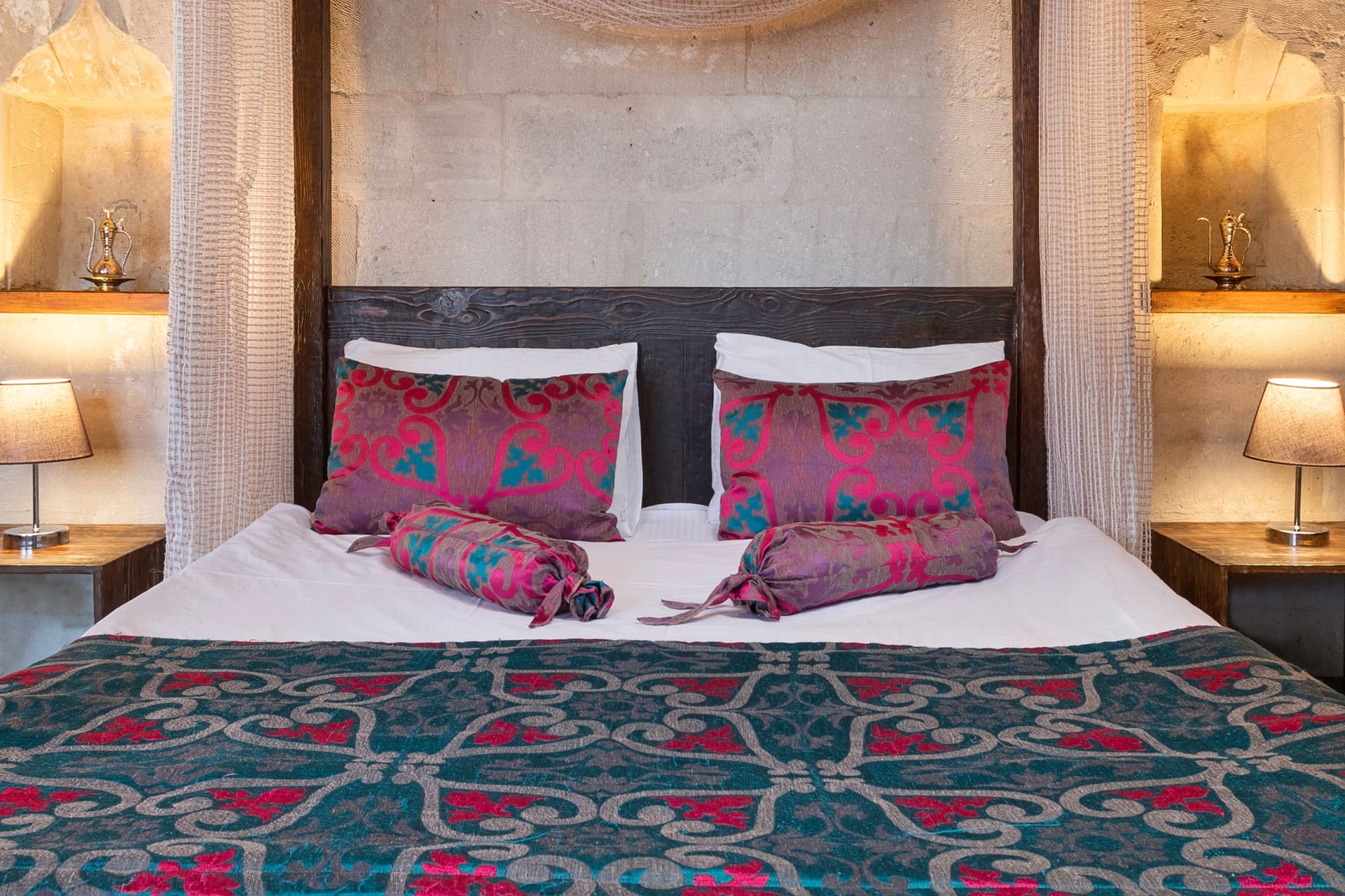 Room 102, Junior Suite: Dark patterned bedspread, lamp on each side, carved wooden panel.