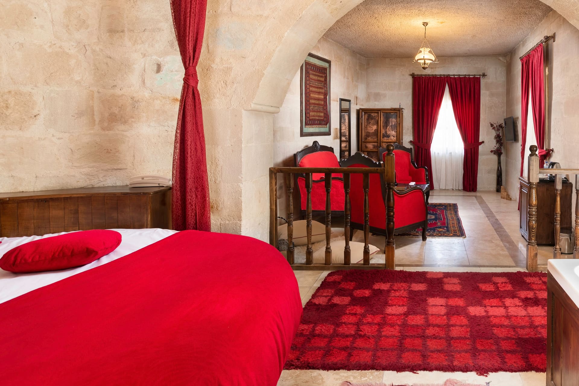 Room 107, King Suite: the bed with a red cover, a wooden dresser and a vase