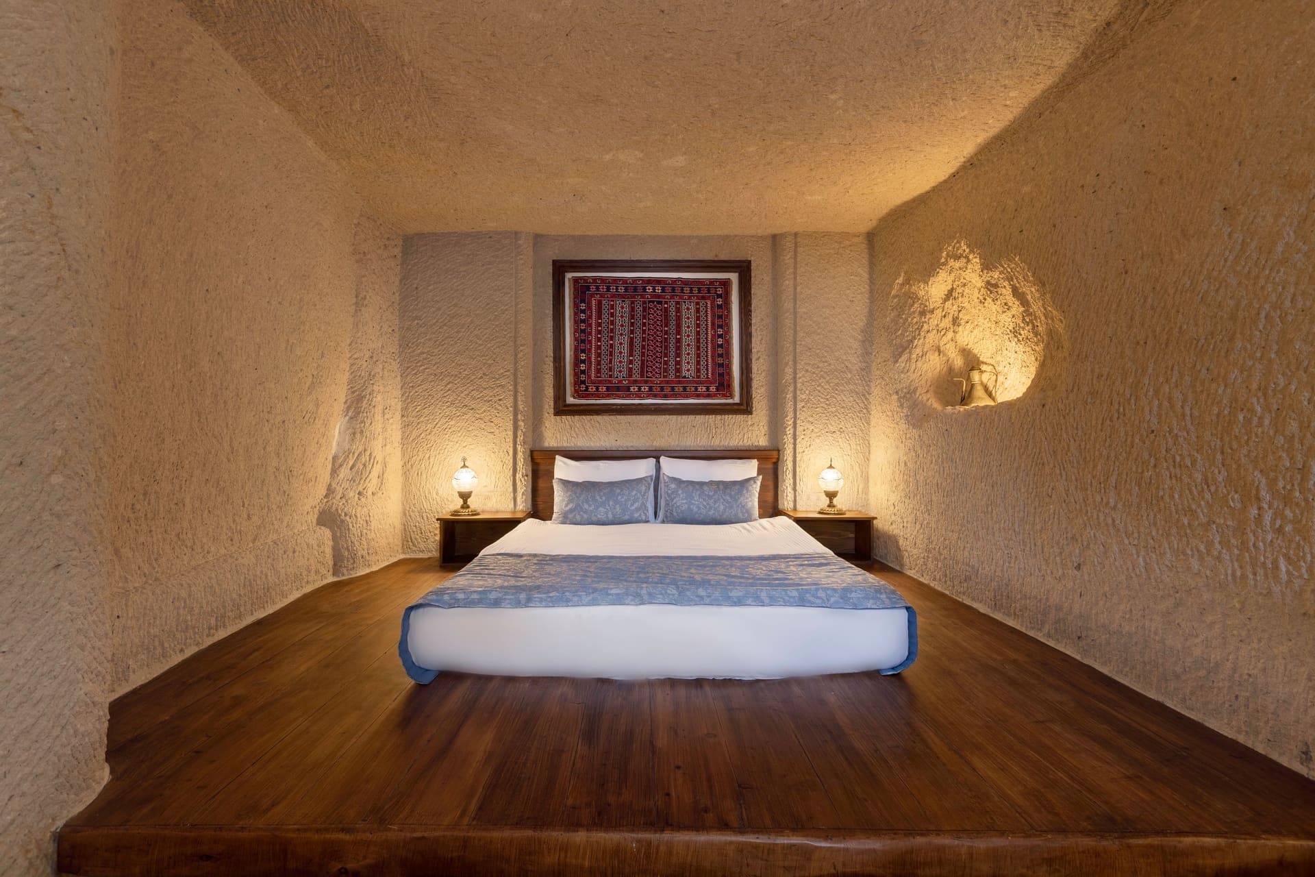 Room 114, Junior Cave Suite: low bed without a headboard, set against the stone wall