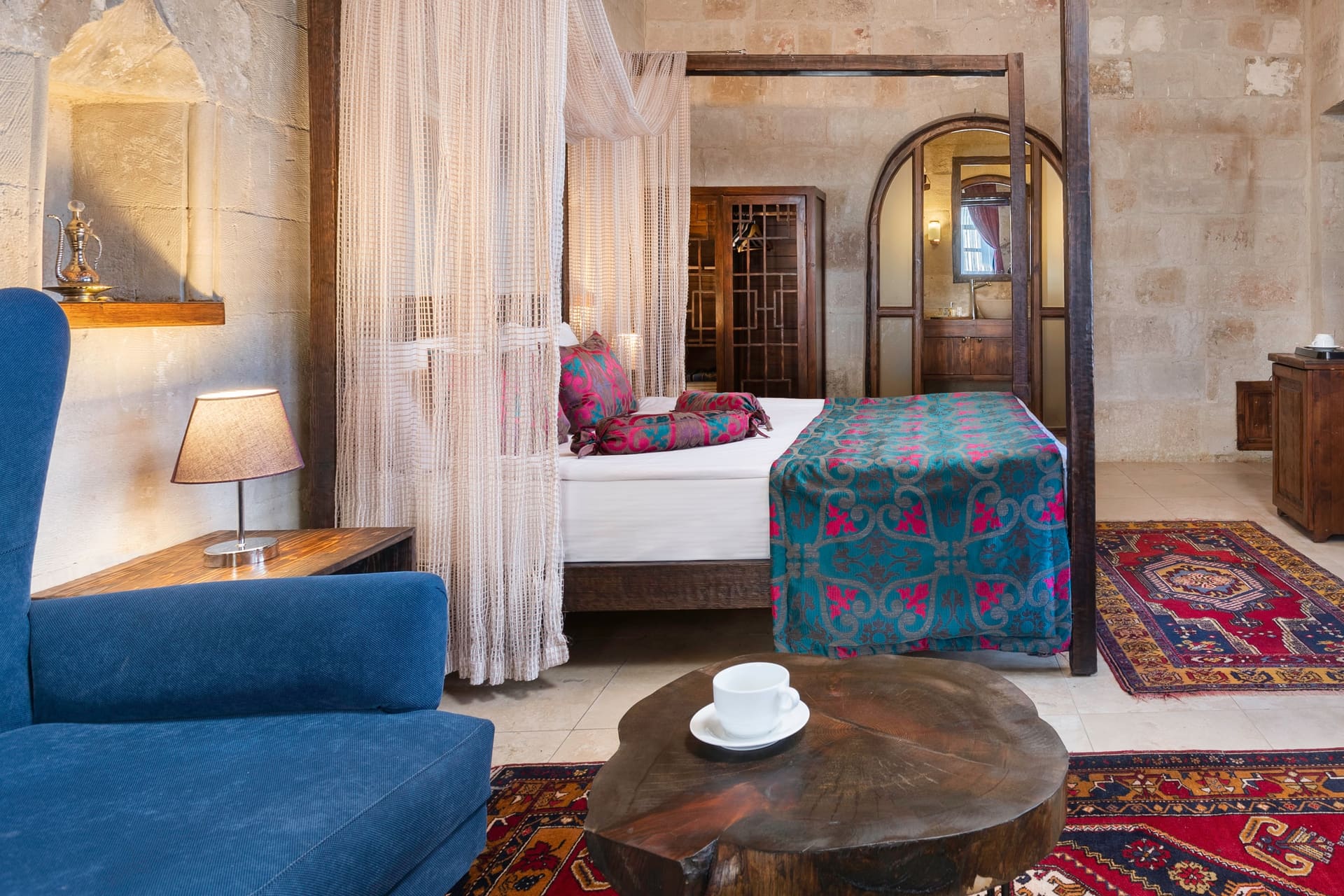 Room 102, Junior Suite: Blue armchair, round table with cups, patterned rug.