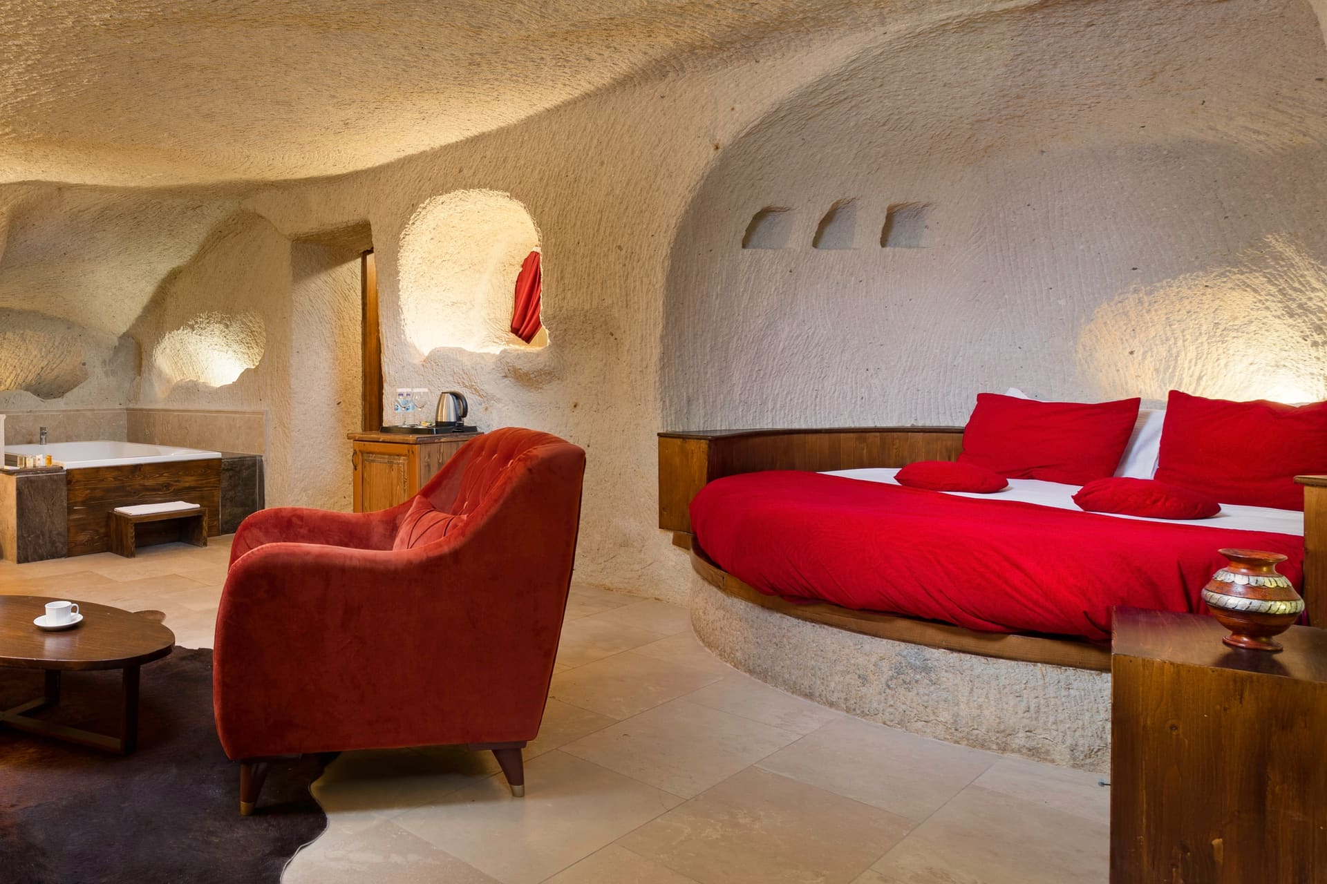 Room 106, King Cave Suite: jacuzzi tub, red-covered bed and the white and rust armchairs in one frame