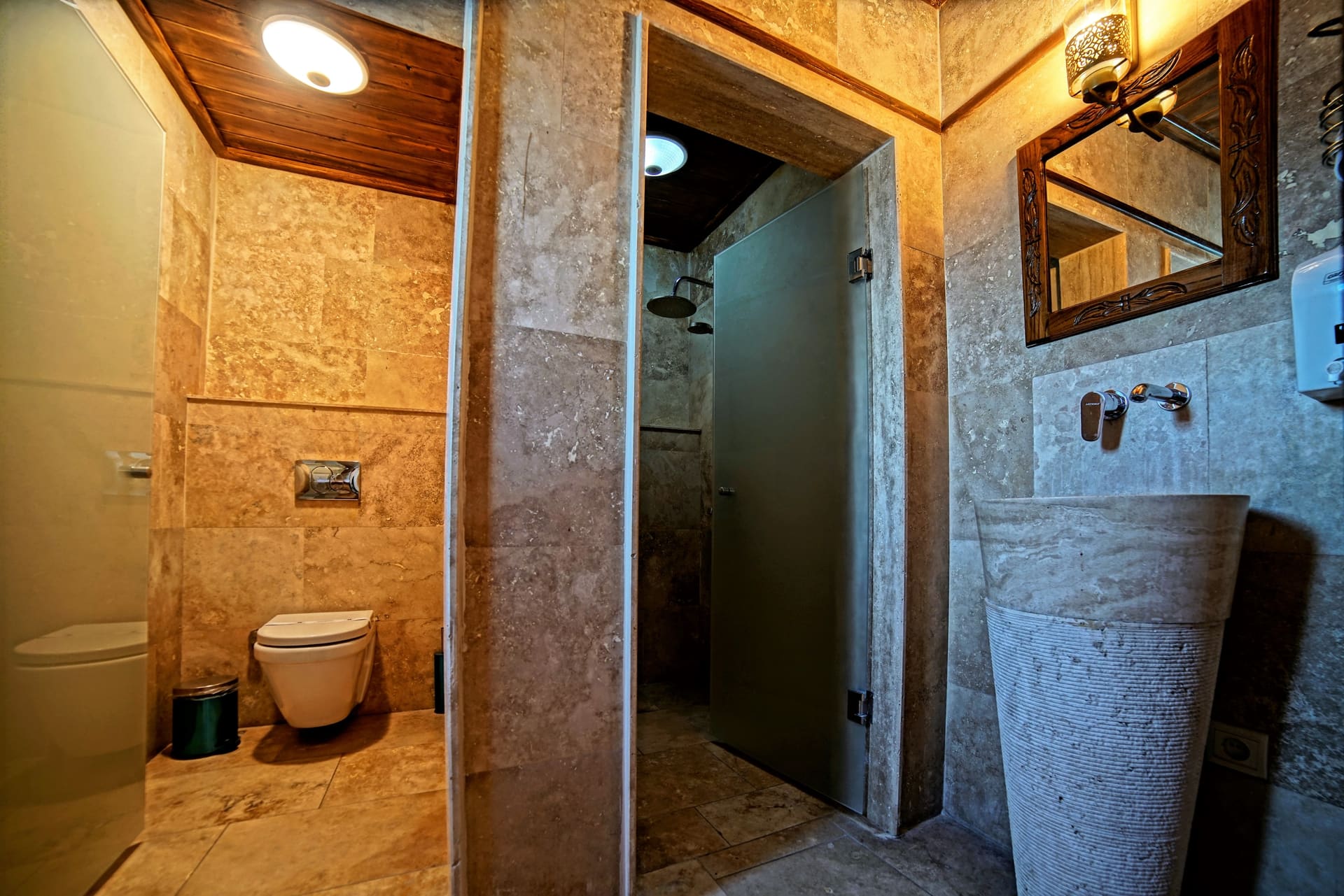 Room 119, Junior Suite: Bathroom, toilet, stone walls, door to shower area, mirror.