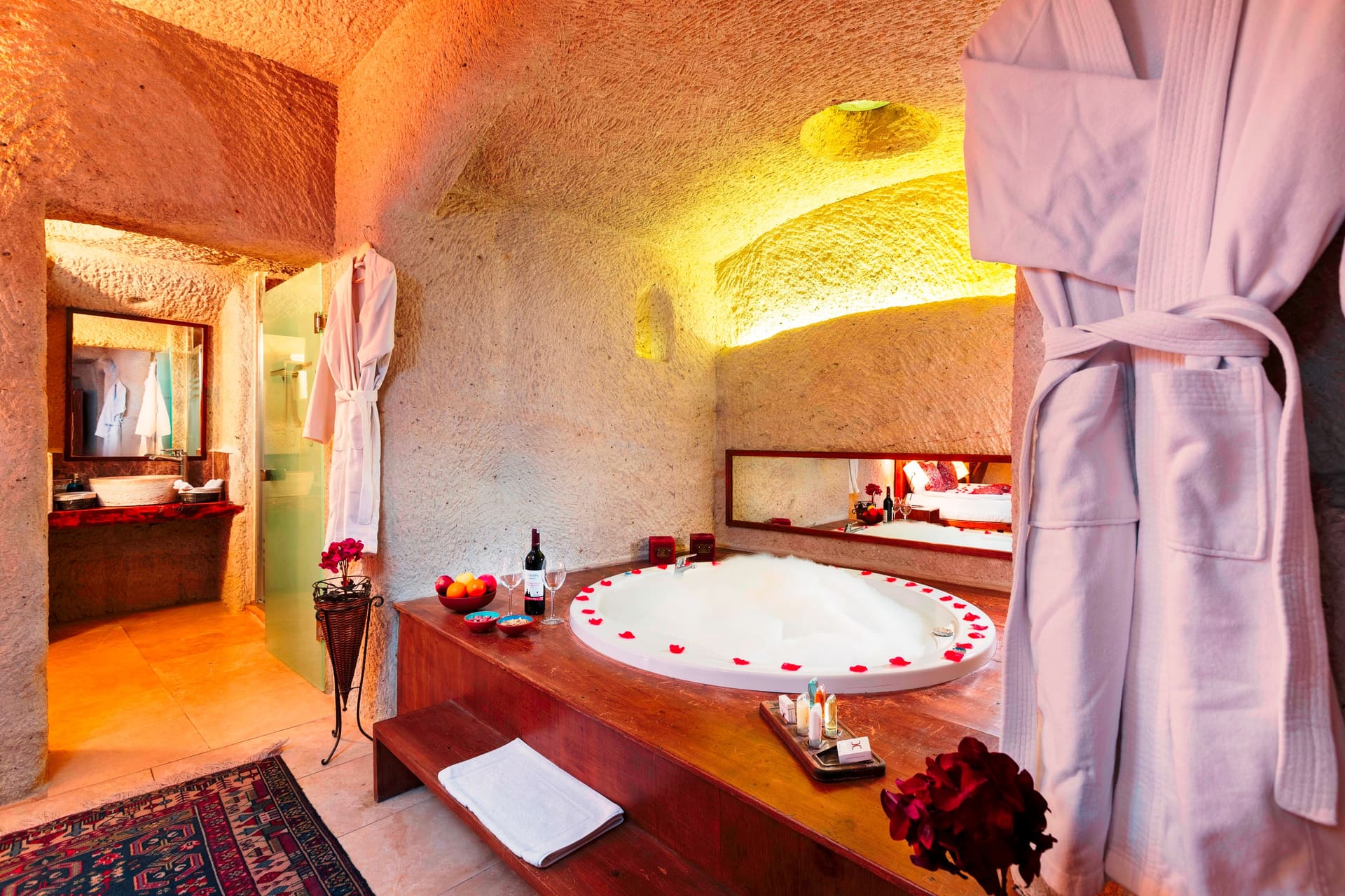 Room 111, King Cave Suite: the round jacuzzi tub with a wine bottle and glasses beside it, robes hanging on either side