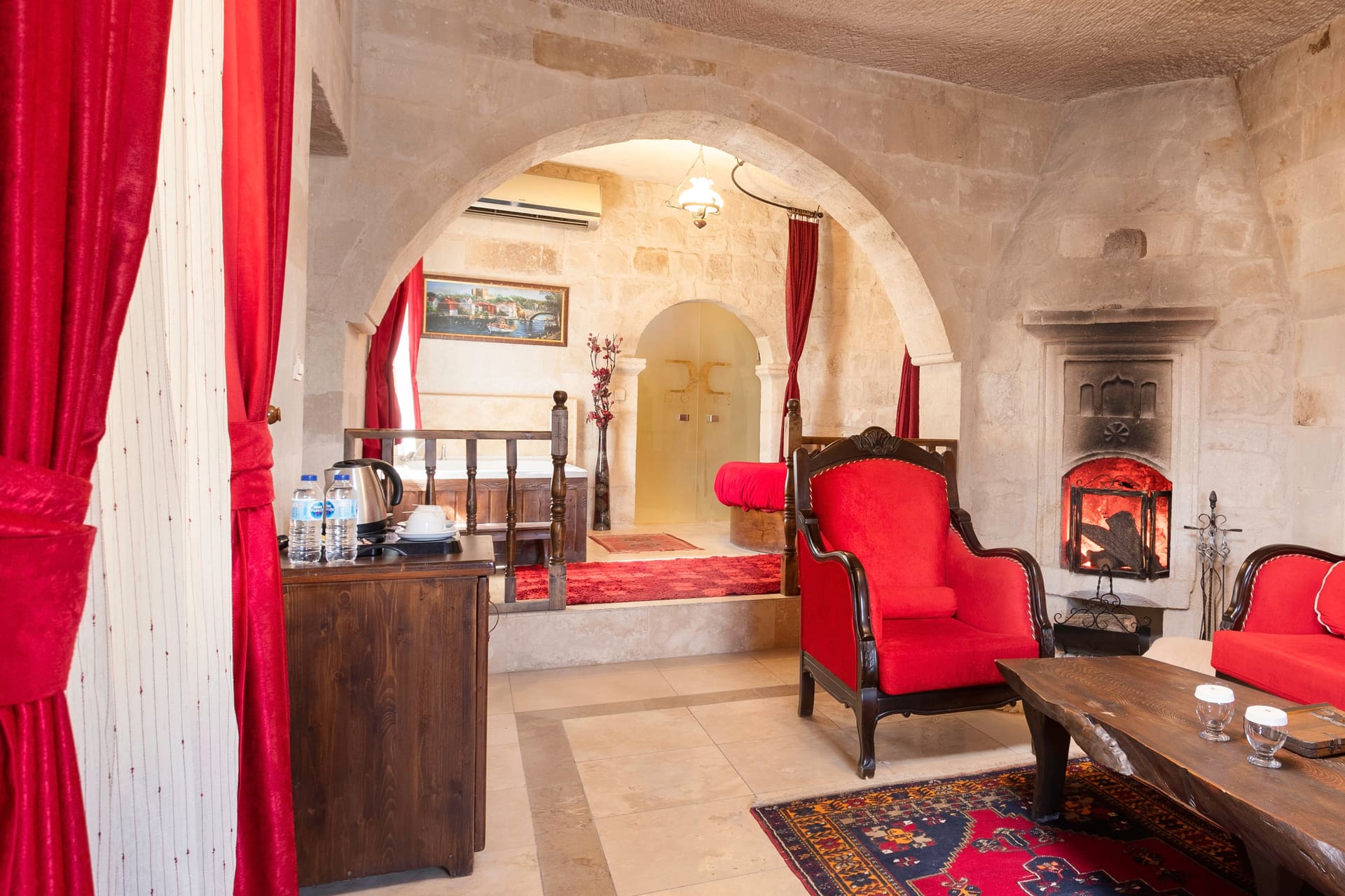 Room 107, King Suite: the red armchair beside the wood-burning stove with cups on the coffee table