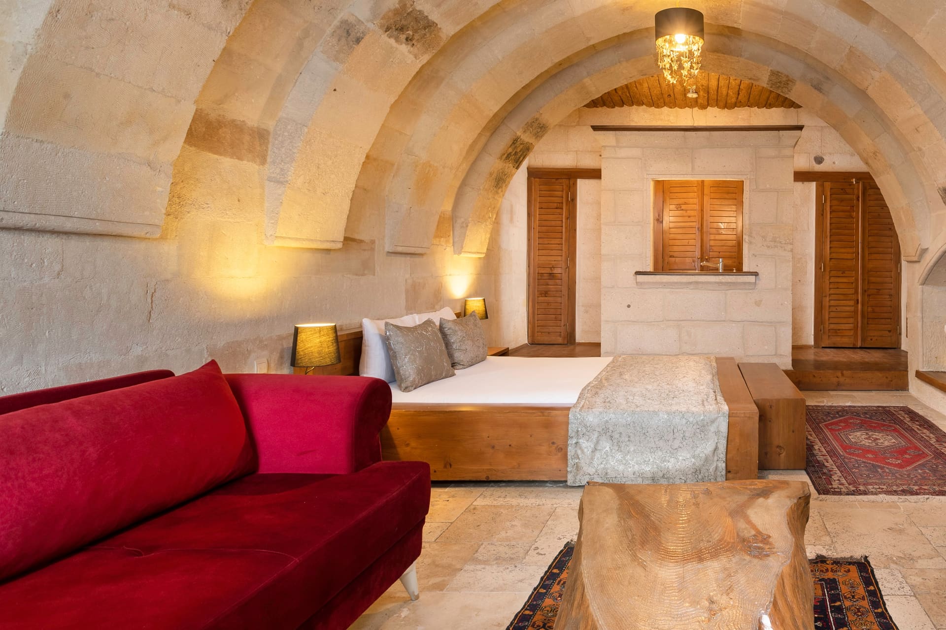 Room 108, Junior Suite: Red sofa, double bed and a shuttered interior window